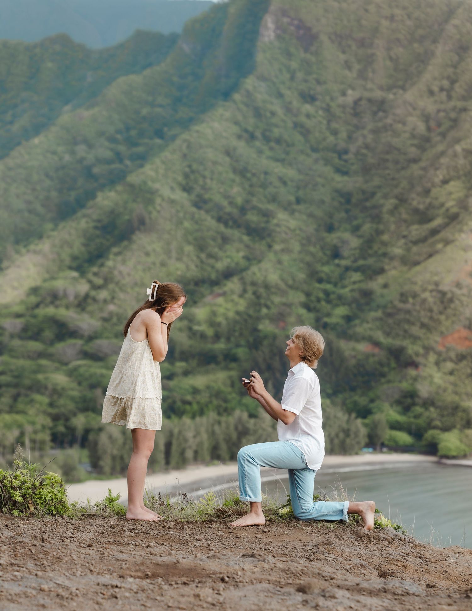 A couple shares a special moment on a mountain overlook with sweeping ocean views.
