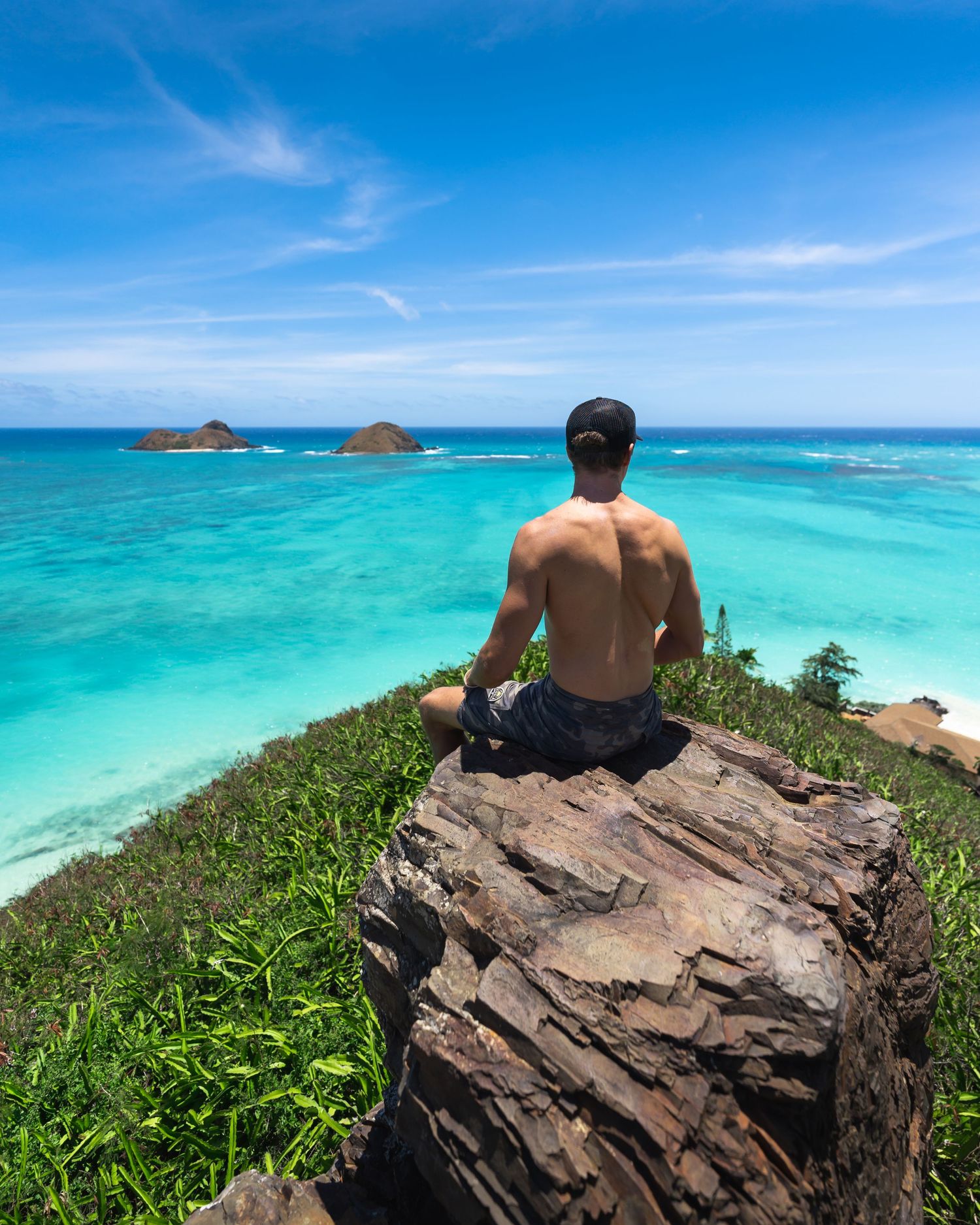 Rocky outcrop overlooking pristine turquoise waters and distant islands in Hawaii.