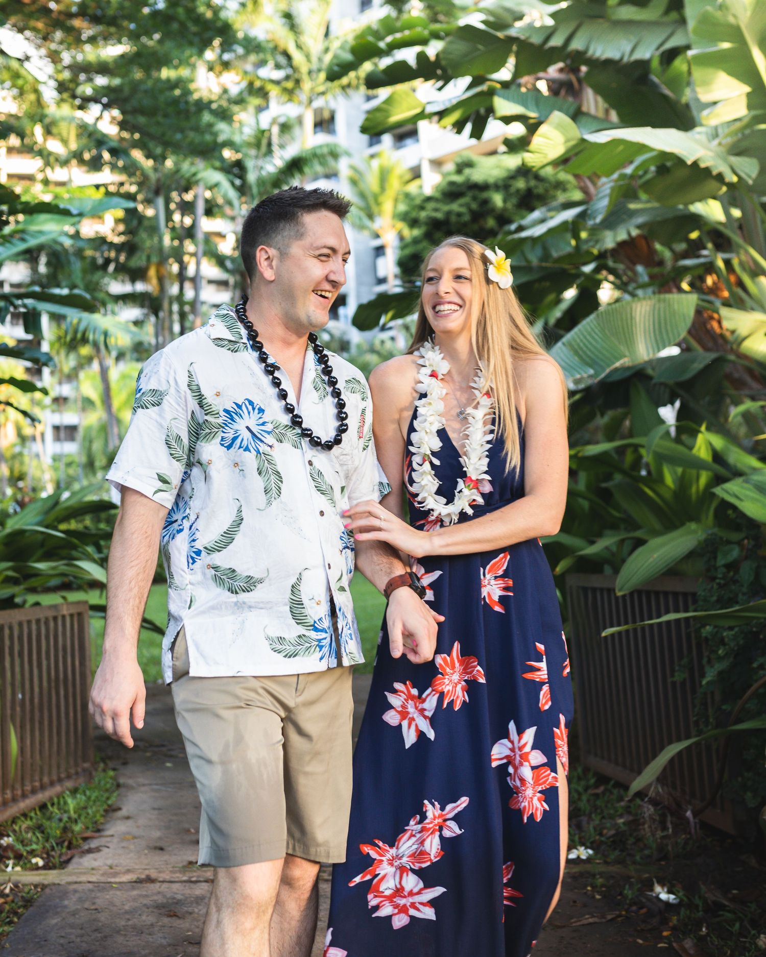 Couple walking through lush tropical garden pathway wearing floral prints.