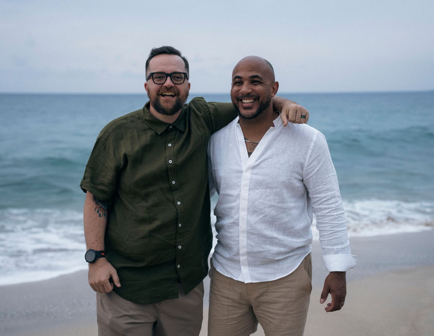 Two people sharing a joyful moment together on a beautiful beach with waves in the background.