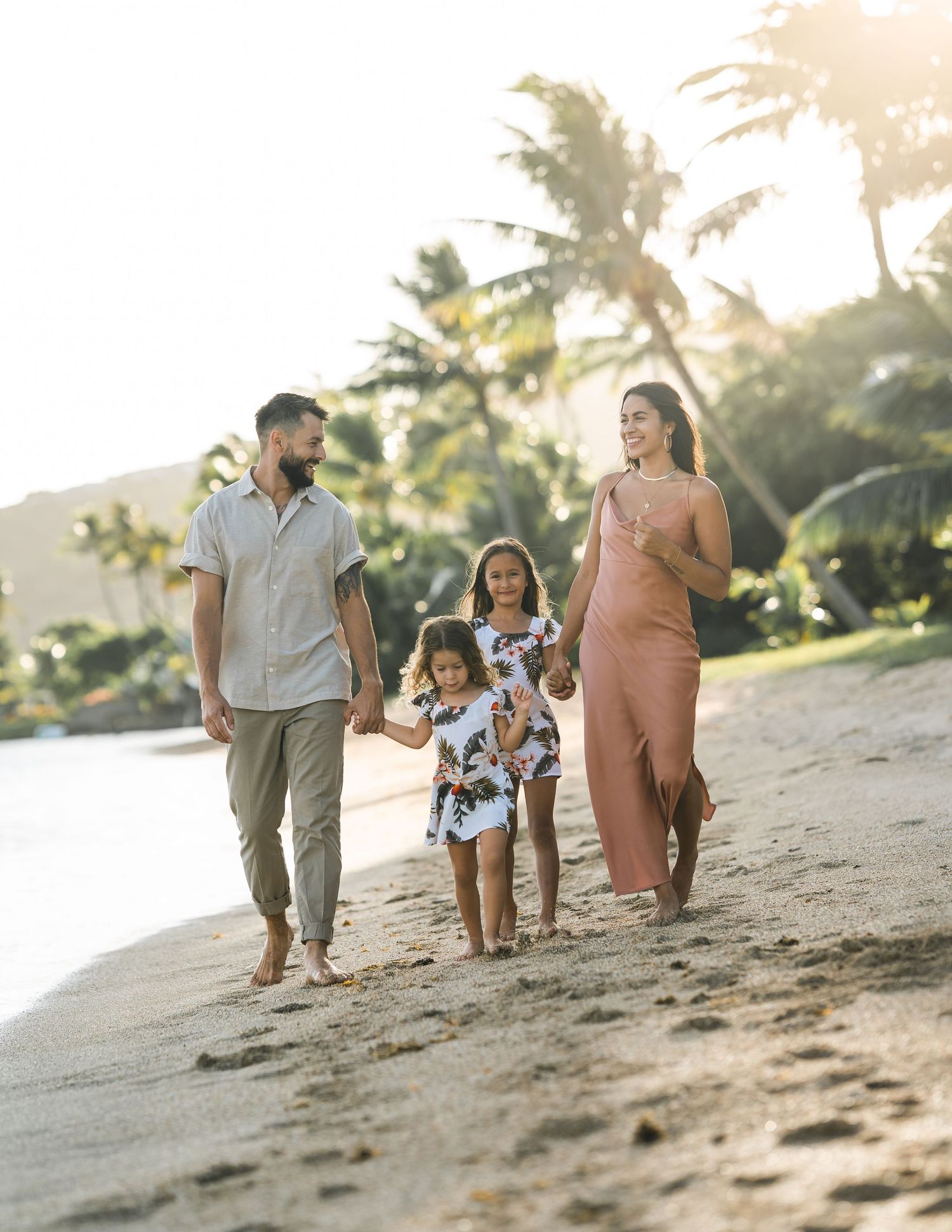 Group walking along a sandy beach during golden hour with palm trees in background.