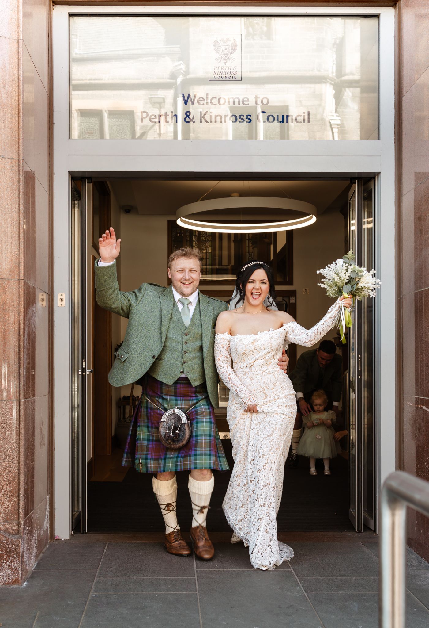 Wedding couple joyfully exits through glass doors in sequence of celebratory shots showing movement and laughter.