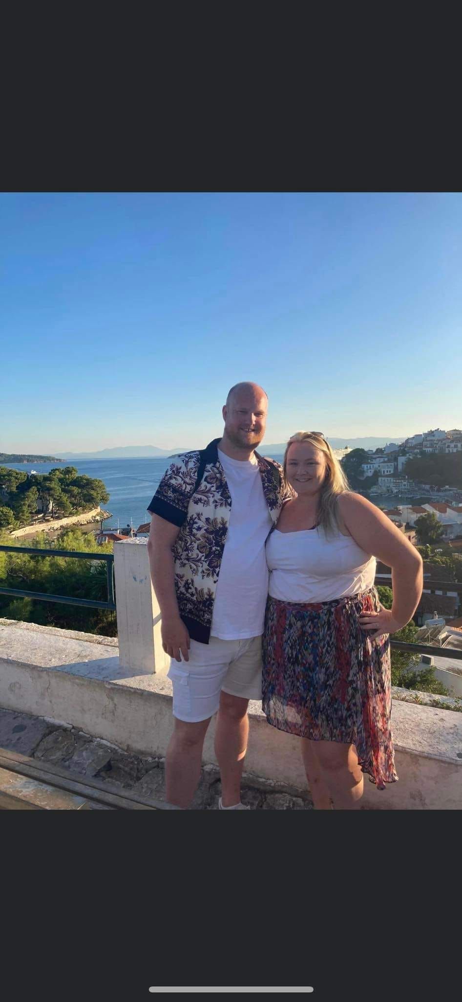 Group enjoying scenic coastal views from a Mediterranean balcony overlooking blue waters and hillside towns.