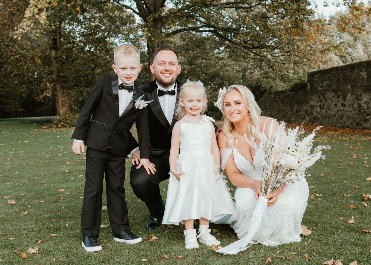 Wedding party relaxing on autumn grass during outdoor photo session.