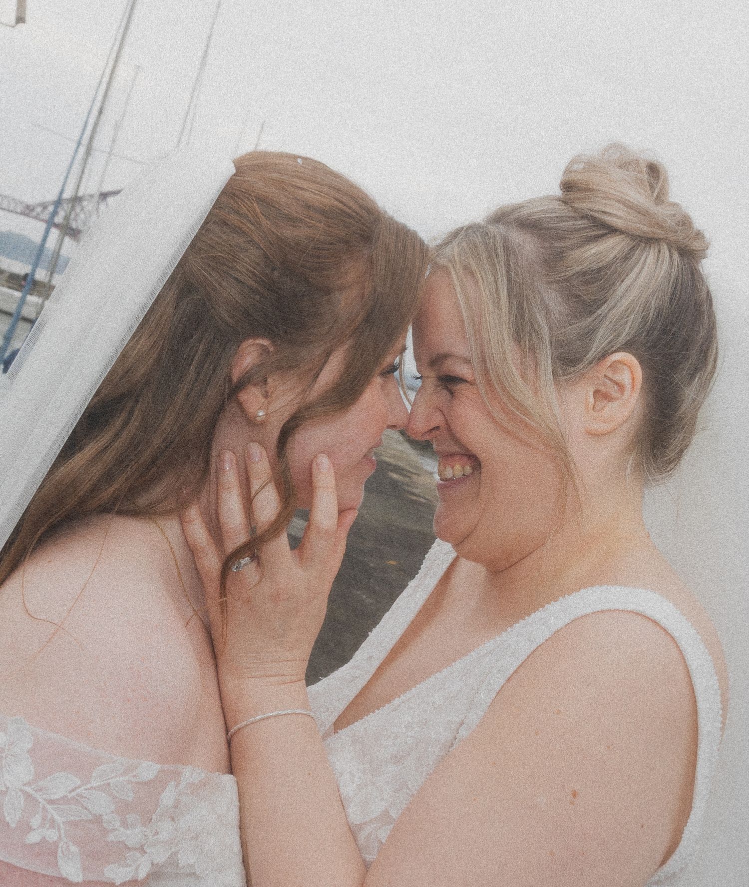 Two brides sharing a joyful moment, smiling and touching foreheads in a loving wedding celebration.