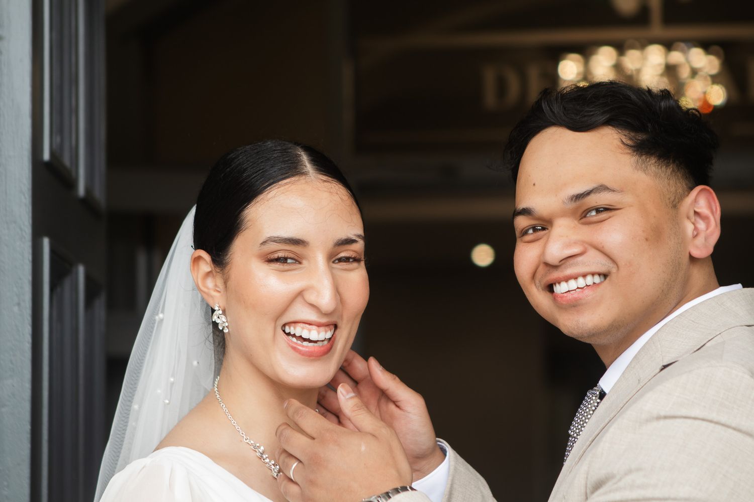 A joyful wedding couple shares a candid moment in a doorway. Dean Park Hotel Fife