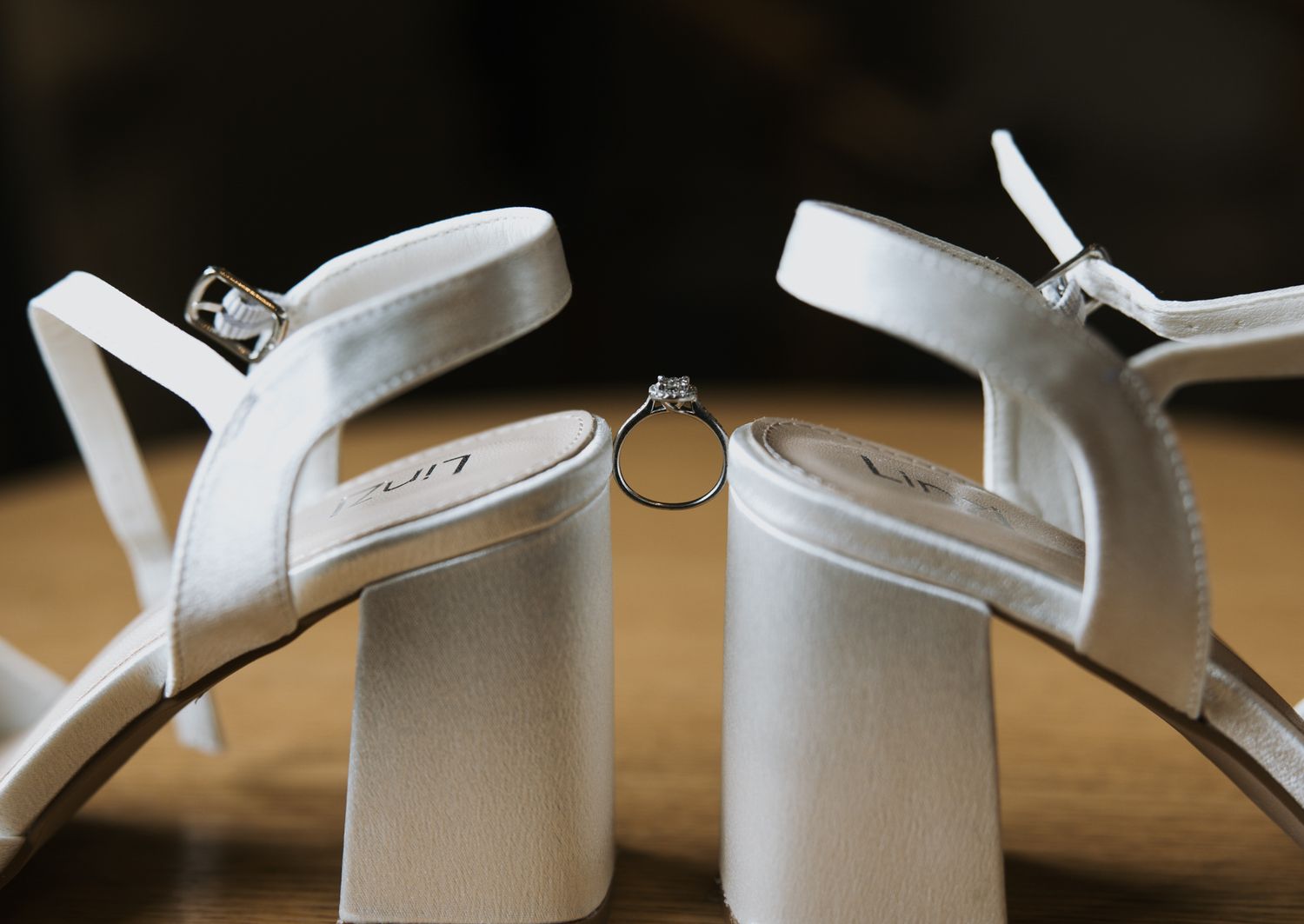 Close-up view of white ceramic mugs hanging on wooden hooks against a dark background.