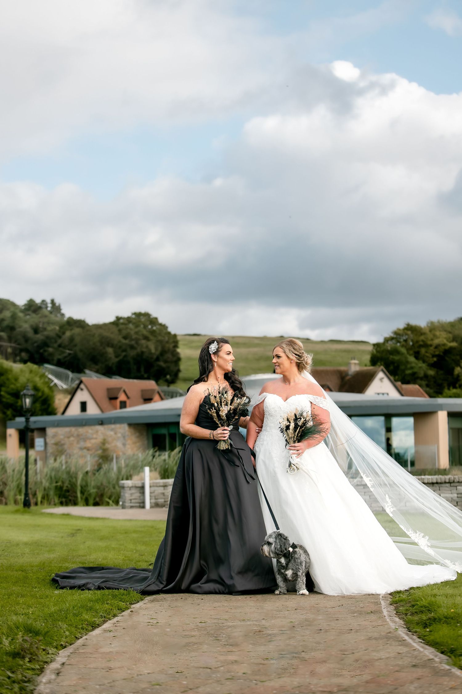 Wedding couple sitting together on stone steps with a scenic countryside backdrop. The Vu, Bathgate