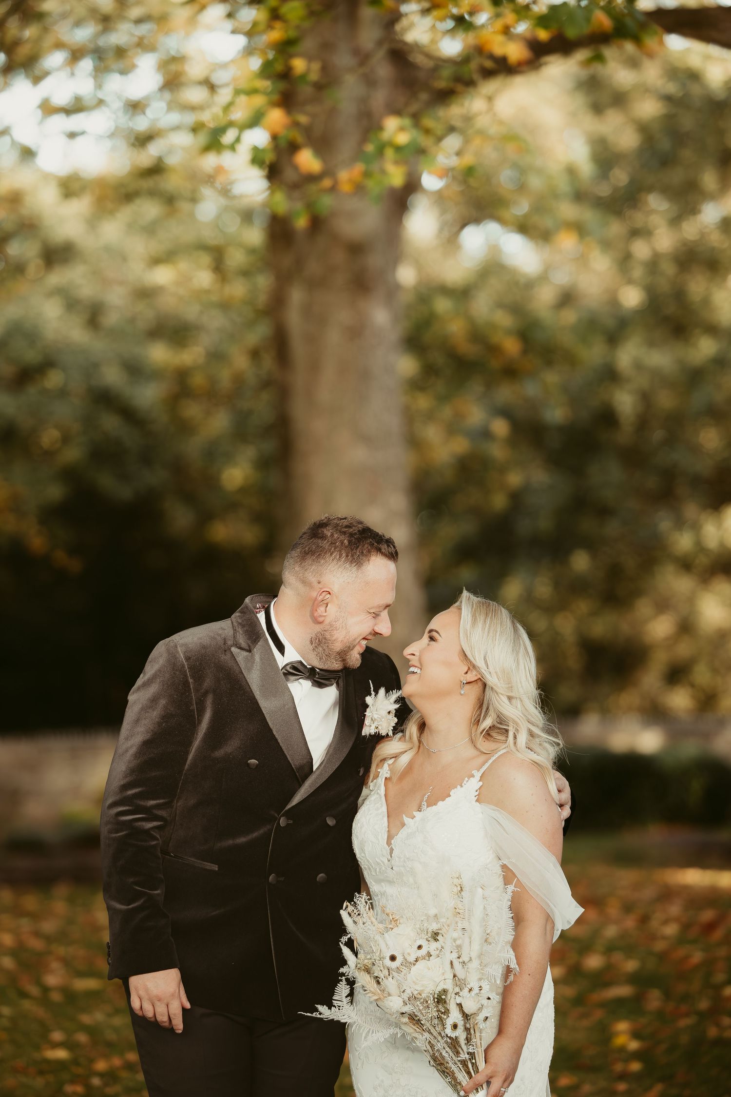 Autumn wedding photoshoot with golden leaves and natural lighting in a park setting.
