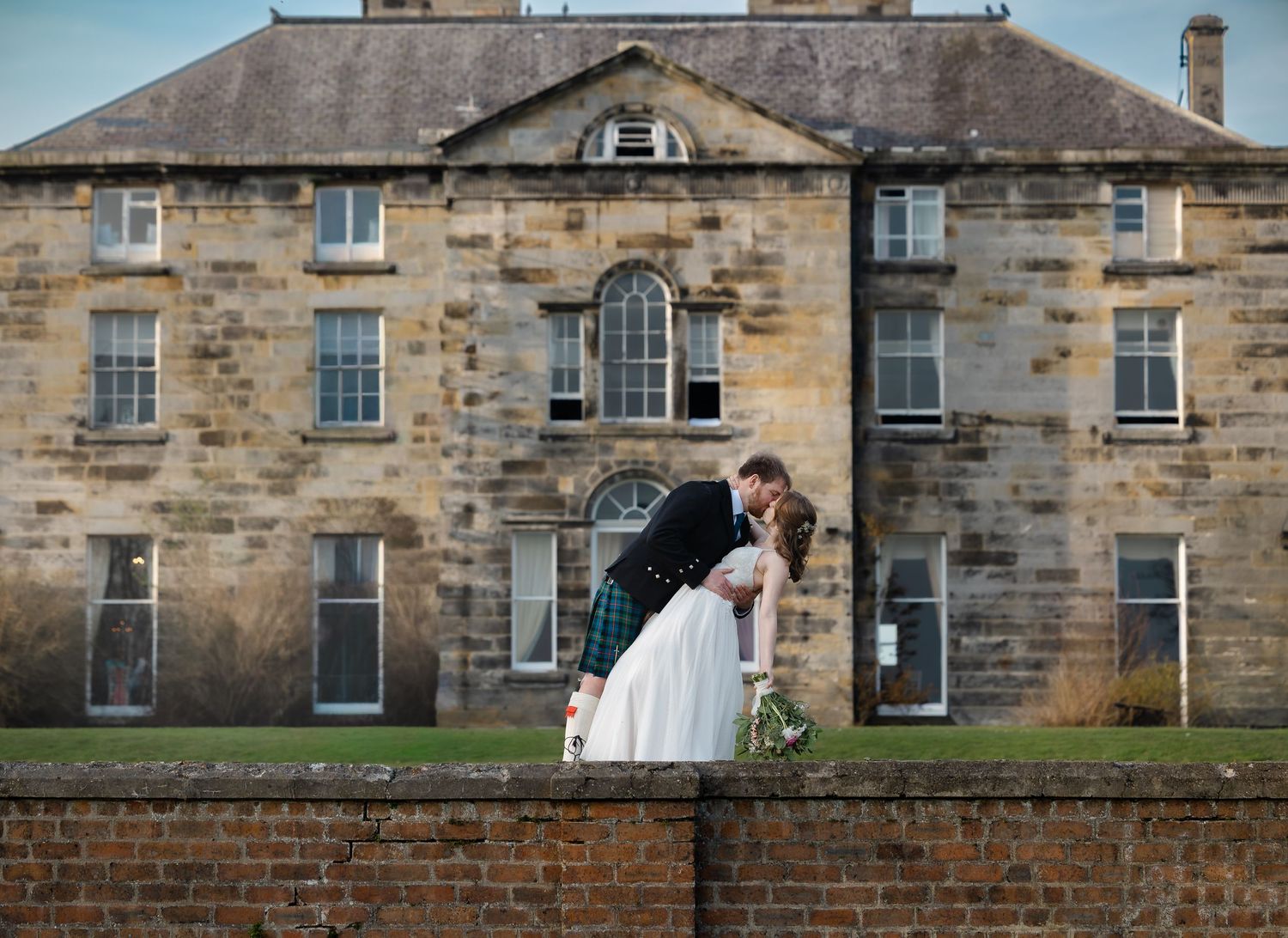 Stone buildings with arched windows and brick walls create a historic architectural panorama in warm sunlight.
