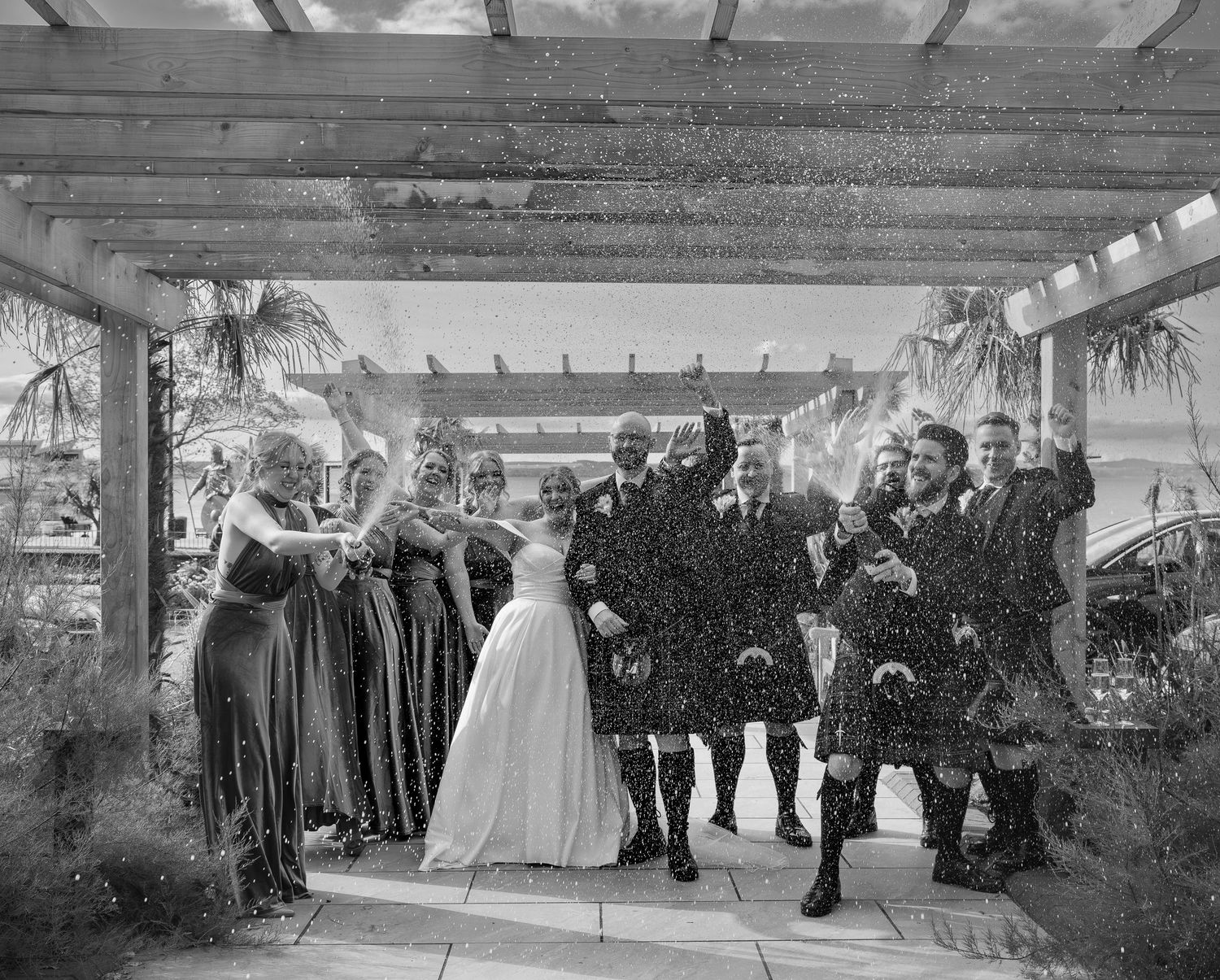 Wedding reception under covered outdoor pavilion with guests gathered for celebration.