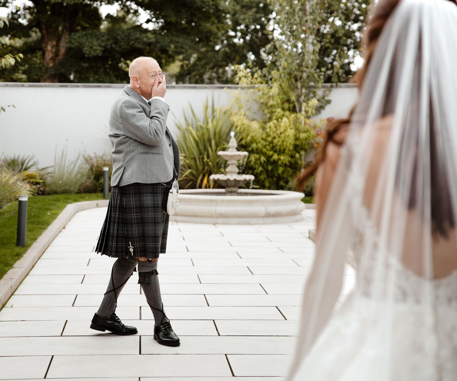 A wedding couple walks along a stone pathway during their outdoor celebration. Redhurst Hotel , Giffnock