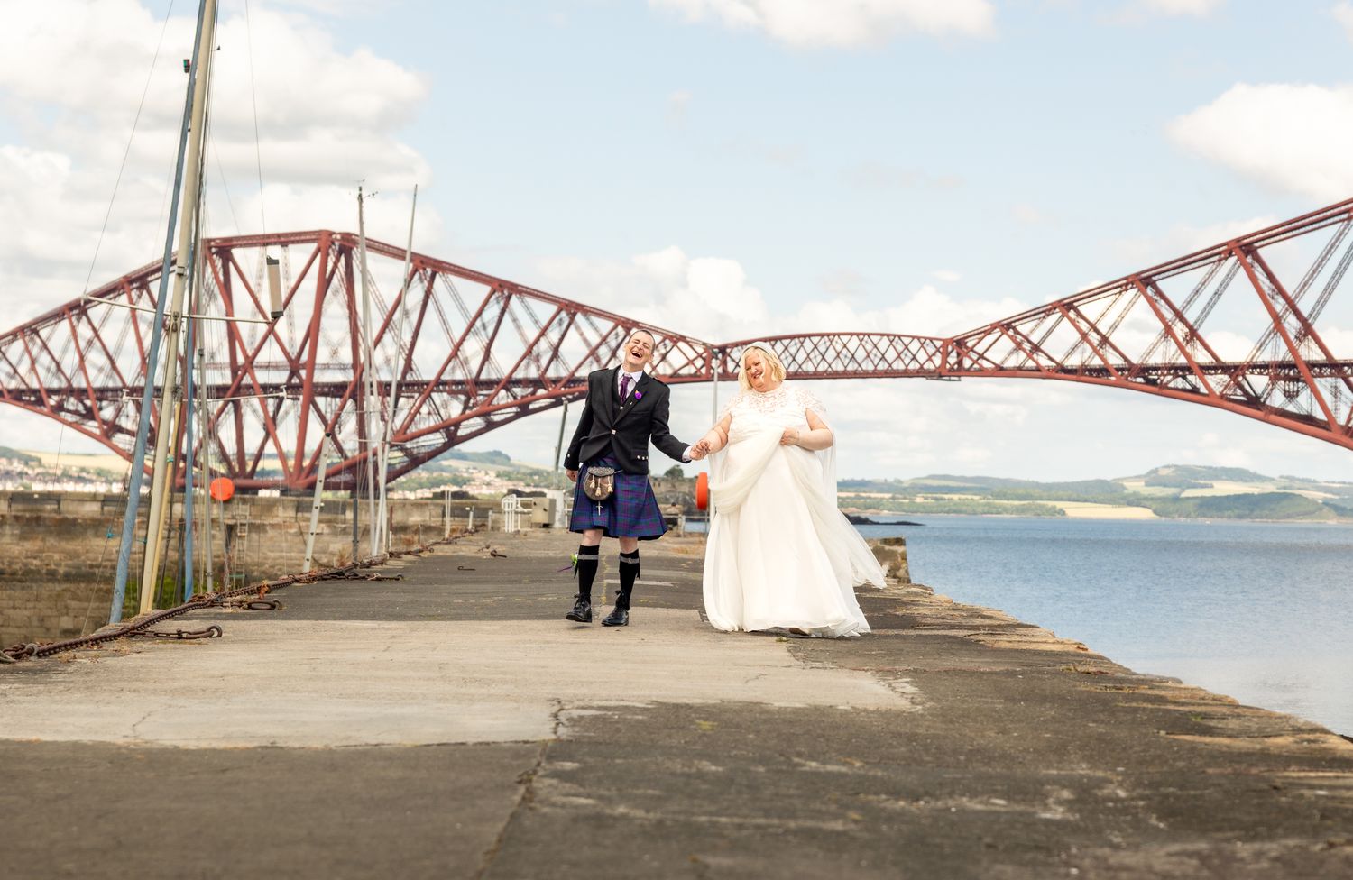Panoramic view of the iconic Forth Bridge railway crossing in Scotland with calm waters and cloudy skies.