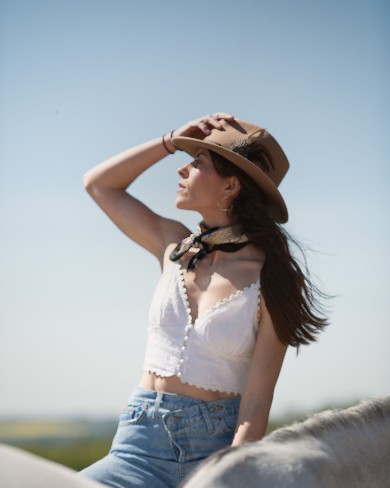 CS Equine Model and Range Rover advert star Andrea Baliarda in soft western fine art portrait with her grey horse under a clear blue sky.
