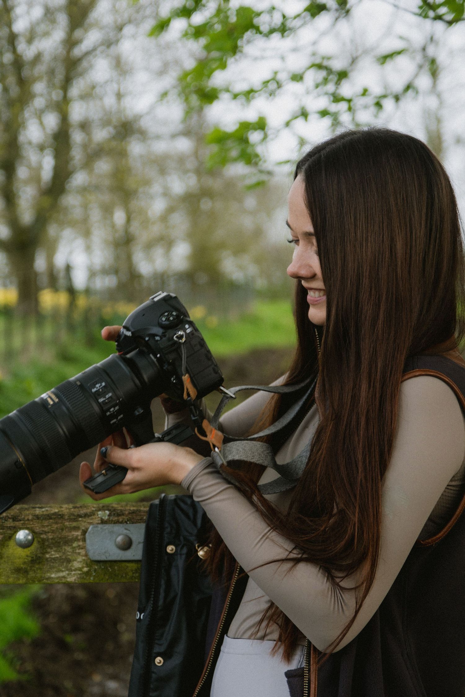 A photographer using professional camera equipment in a natural outdoor setting.