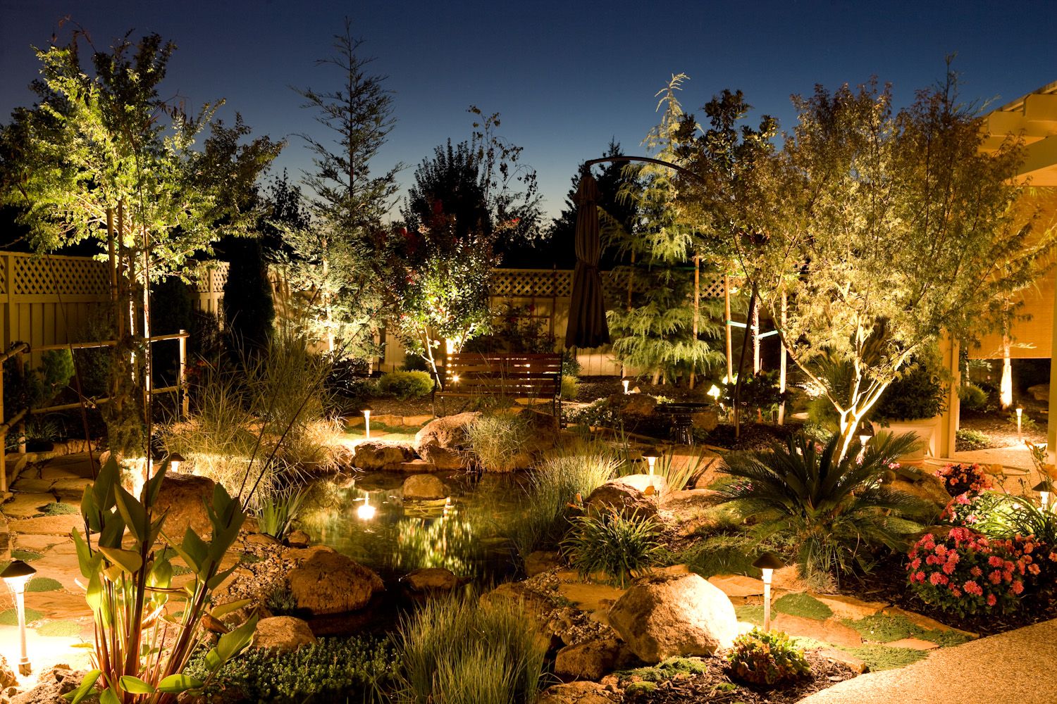 Beautifully lit garden landscape with illuminated trees and pathways creating a magical nighttime atmosphere.