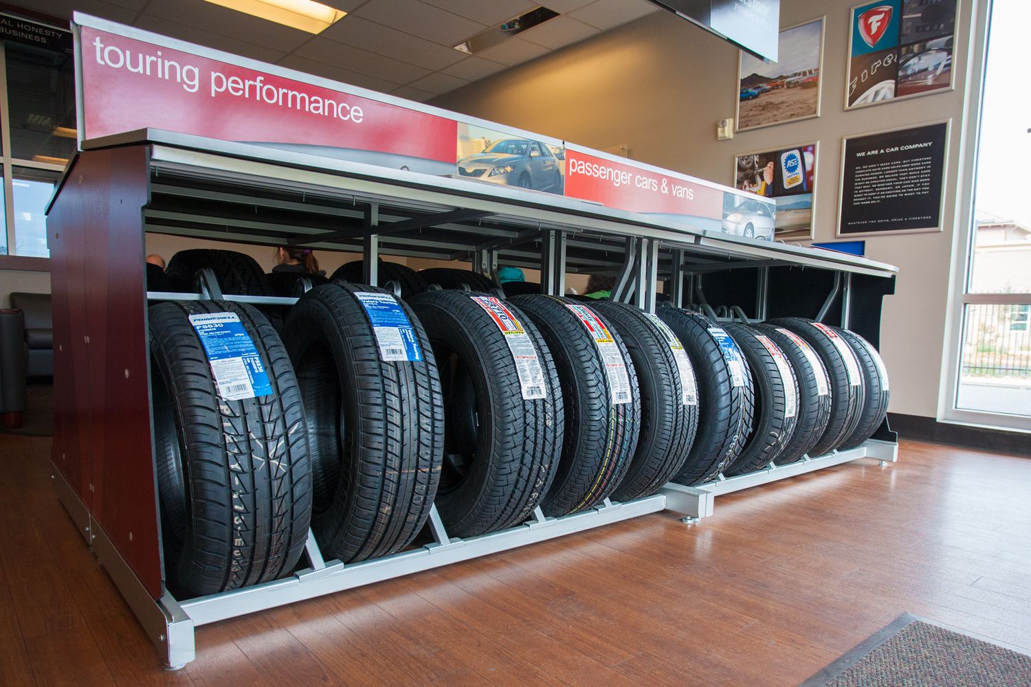 Row of new car tires displayed on retail shelf with performance tire signage.