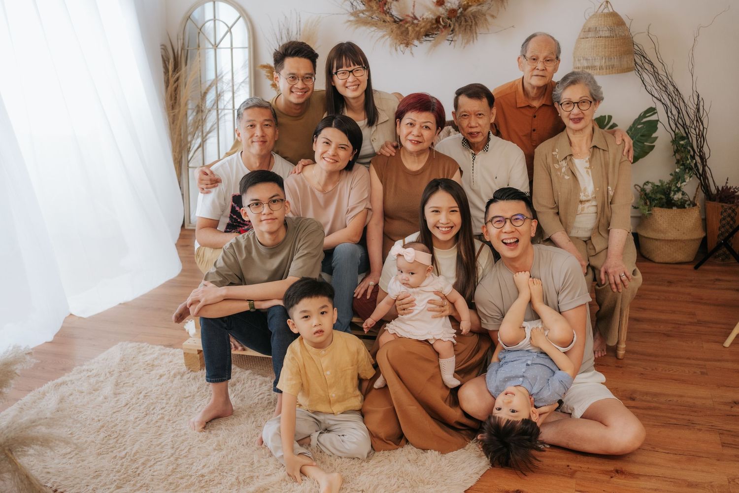 A group of people sitting together in casual attire on a wooden floor in a bright indoor setting一群人穿著休閒服裝，坐在明亮的室內木地板上。