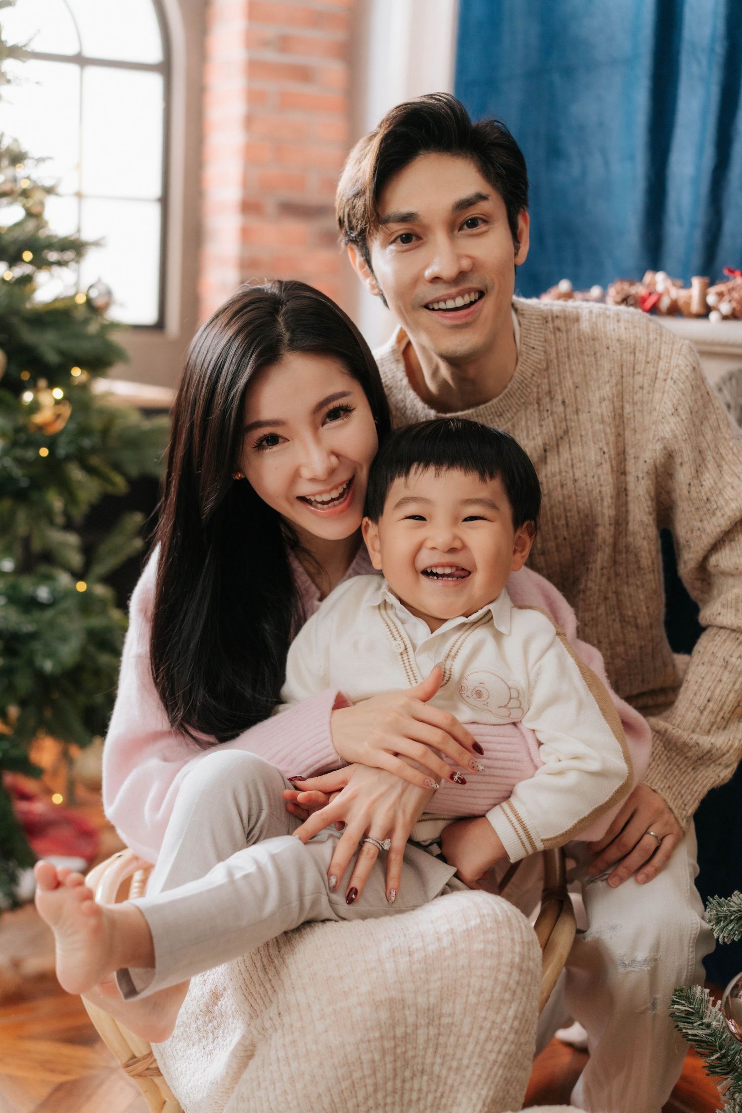A family shares joyful moments together in front of a Christmas tree during a holiday photoshoot.一家人在聖誕樹前拍攝節慶照片，共享歡樂時光。