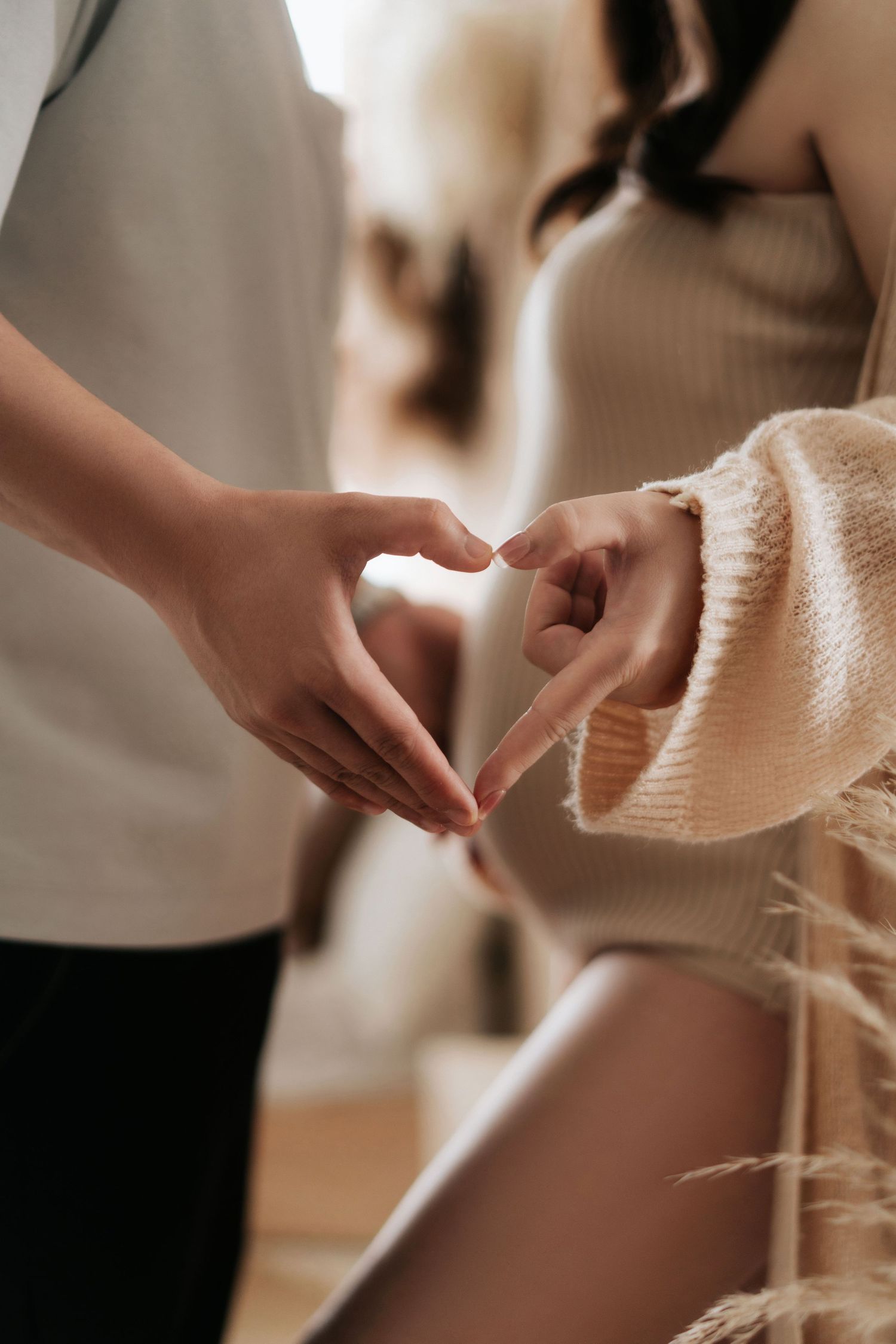 Hands carefully unravel and inspect a beige knit fabric texture in warm lighting.在溫暖的燈光下，雙手小心翼翼地展開並檢查一塊米色針織布料的質地。