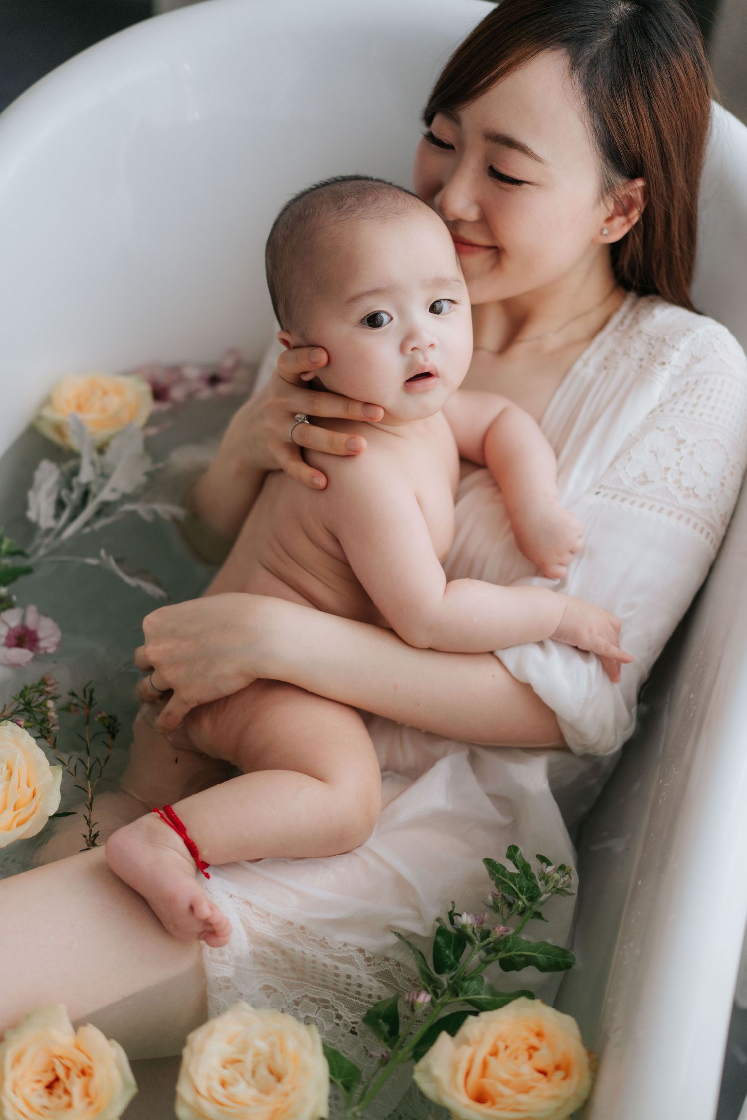 Mother and baby relaxing together in a floral bath surrounded by yellow roses and greenery.母親和寶寶在鮮花簇擁的浴缸中放鬆身心，周圍環繞著黃色玫瑰和綠色植物。
