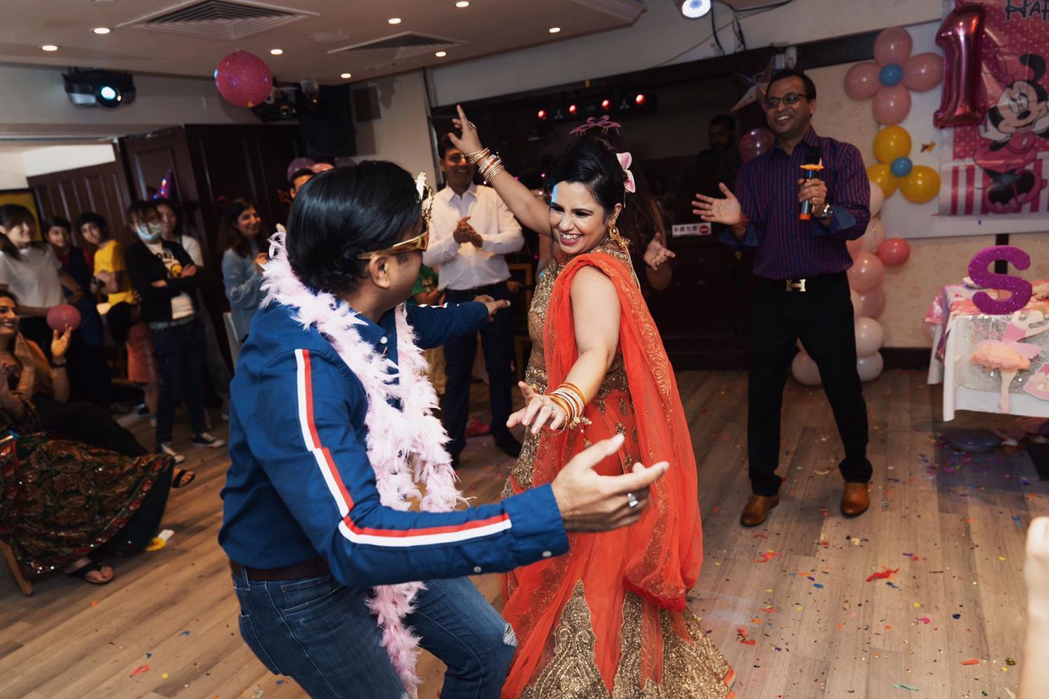 People dancing together at a lively social event with festive decorations and lighting in the background.人們在熱鬧的社交活動中一起跳舞，背景是喜慶的裝飾和燈光。