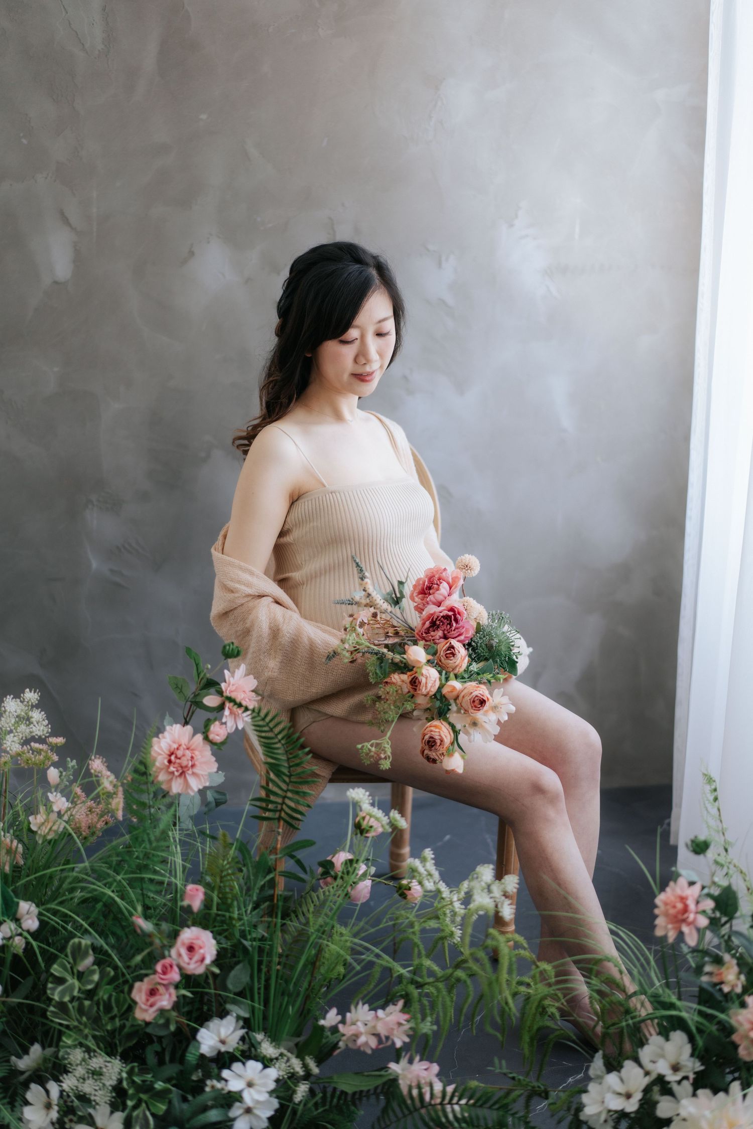 Artistic portrait series with pink roses and ferns against a grey backdrop, capturing soft romantic poses in beige attire.