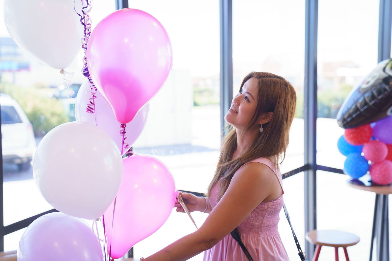 People celebrate at a party with pink and white balloons decorating the bright indoor space.人們在派對上慶祝，粉紅色和白色的氣球裝飾著明亮的室內空間。
