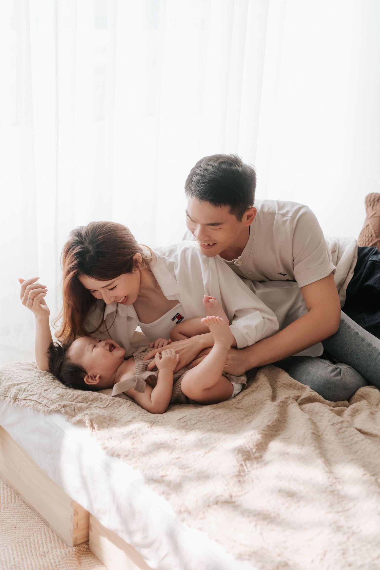 A family shares a tender moment together while relaxing on a cozy bed with white linens一家人躺在鋪著白色床單的舒適床上，享受溫馨的時刻。