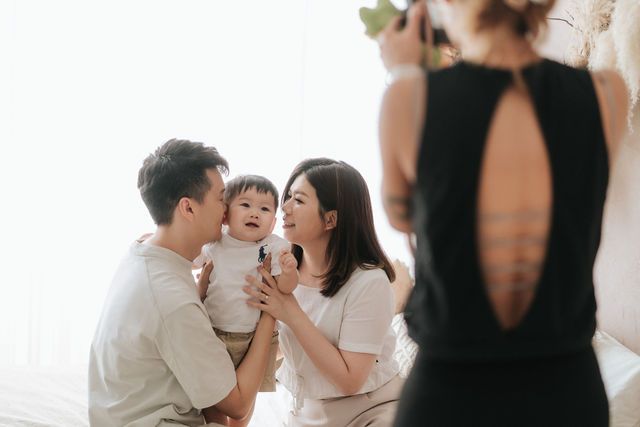 A happy Asian family with parents holding a baby, sharing a tender moment together in a bright, cozy room.