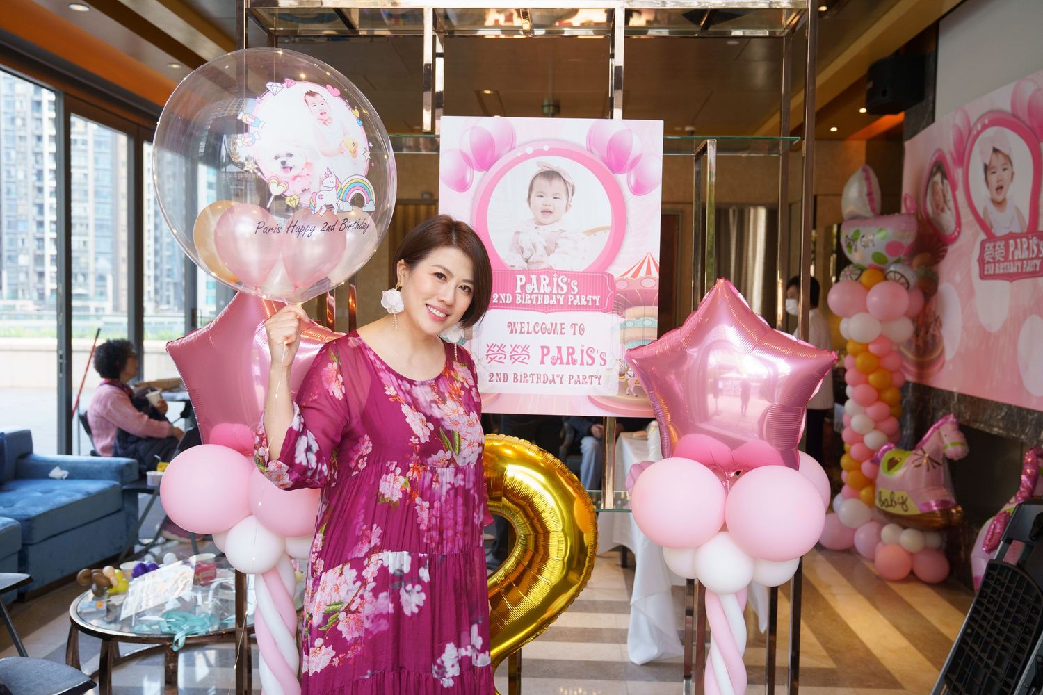 Pink and gold balloons decorate an elegant indoor party space with tables and chairs arranged for a celebration.粉紅色和金色的氣球裝飾著優雅的室內派對場地，桌椅擺放整齊