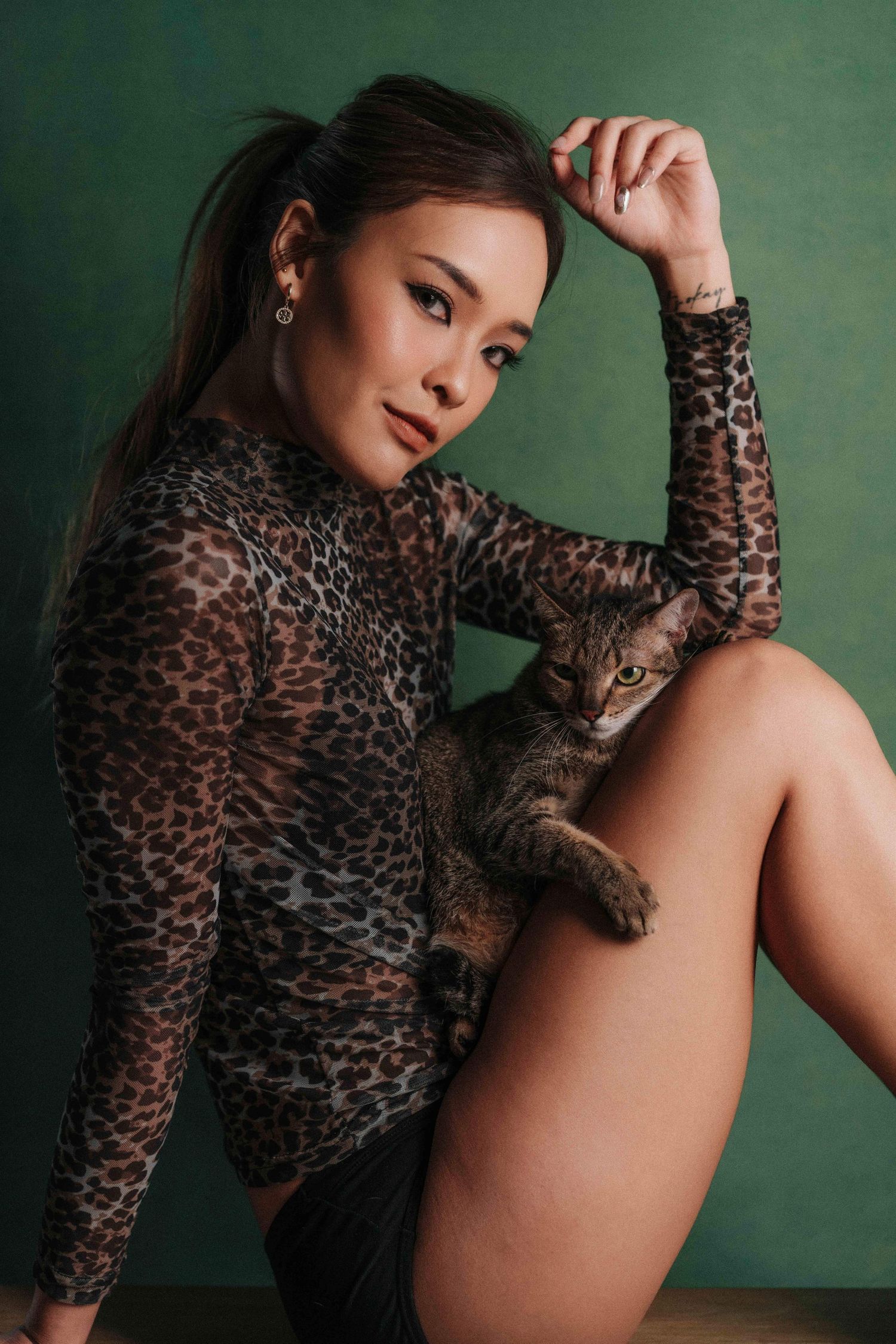 Fashion model poses in sheer leopard print top against green backdrop in artistic boudoir photoshoot series.時尚模特兒身穿薄紗豹紋上衣，在綠色背景下擺出各種姿勢