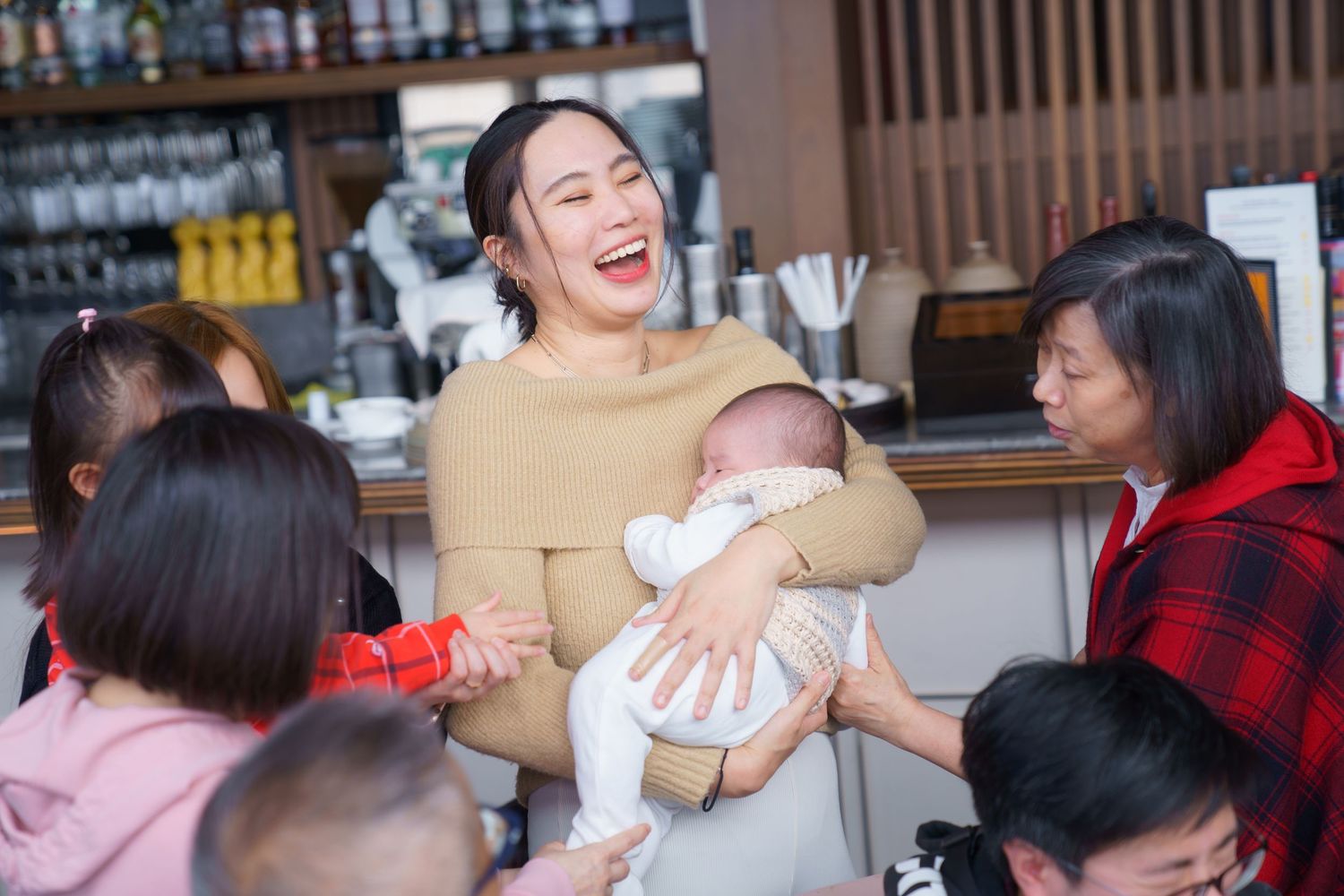 A group of people sharing a lively meal together at a restaurant with wooden decor and warm lighting.一群人在裝潢以木質為主、燈光溫暖的餐廳裡一起享用美食，氣氛十分熱鬧。
