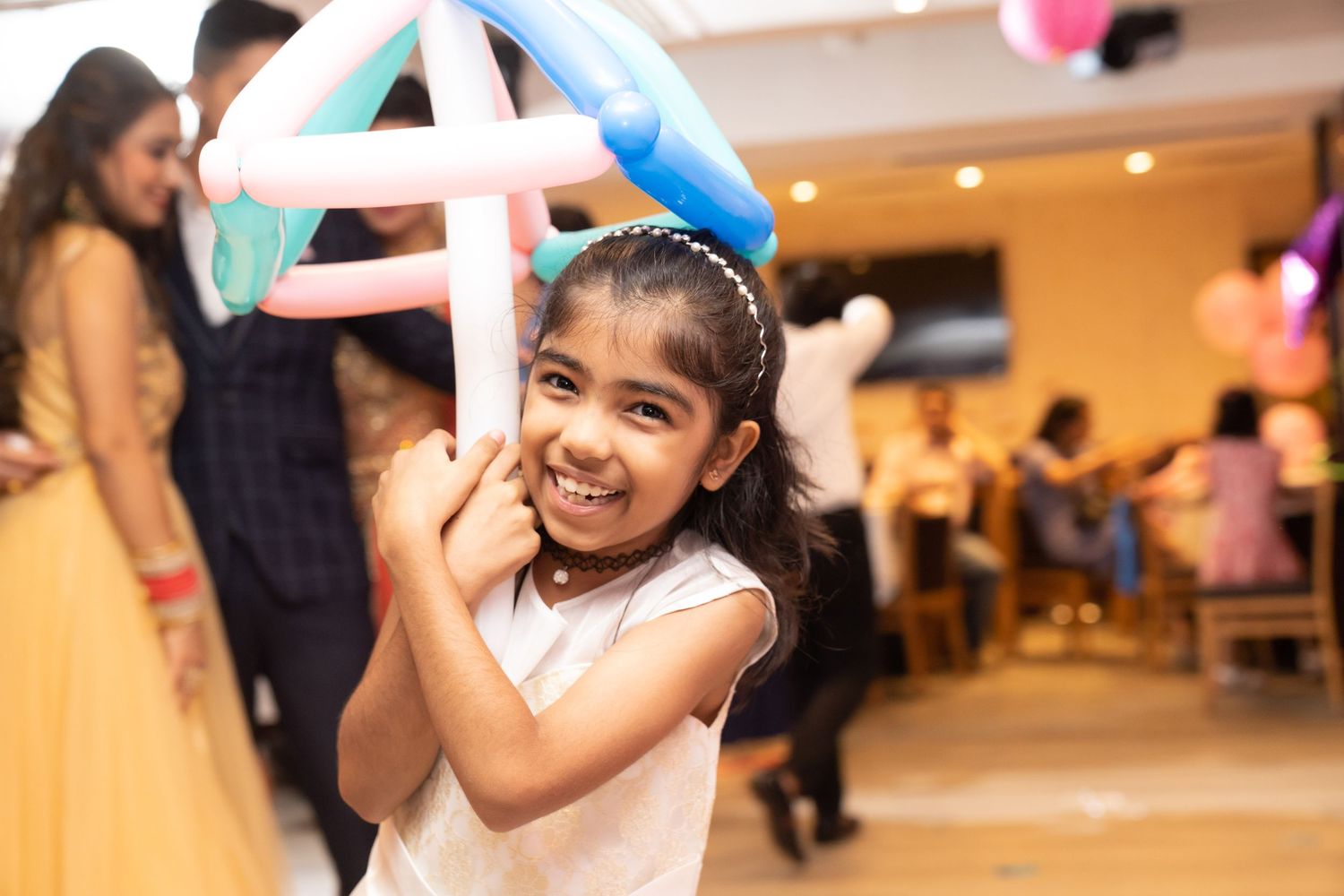 Children play with colorful balloons at an indoor party venue decorated with pink and blue decorations.孩子們在裝飾著粉紅色和藍色飾品的室內派對場地玩著五彩繽紛的氣球。