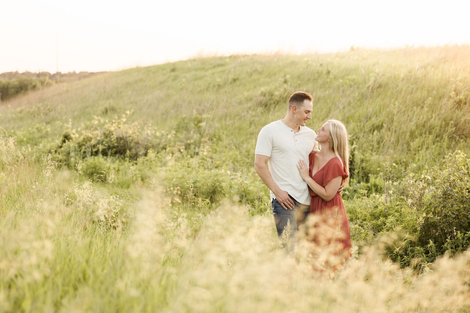 Candid lifestyle photos of family in golden field during sunset.