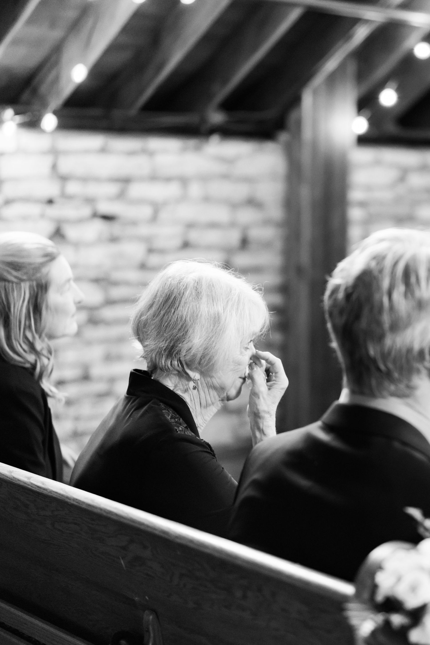 Black and white image of grandma crying watching wedding.