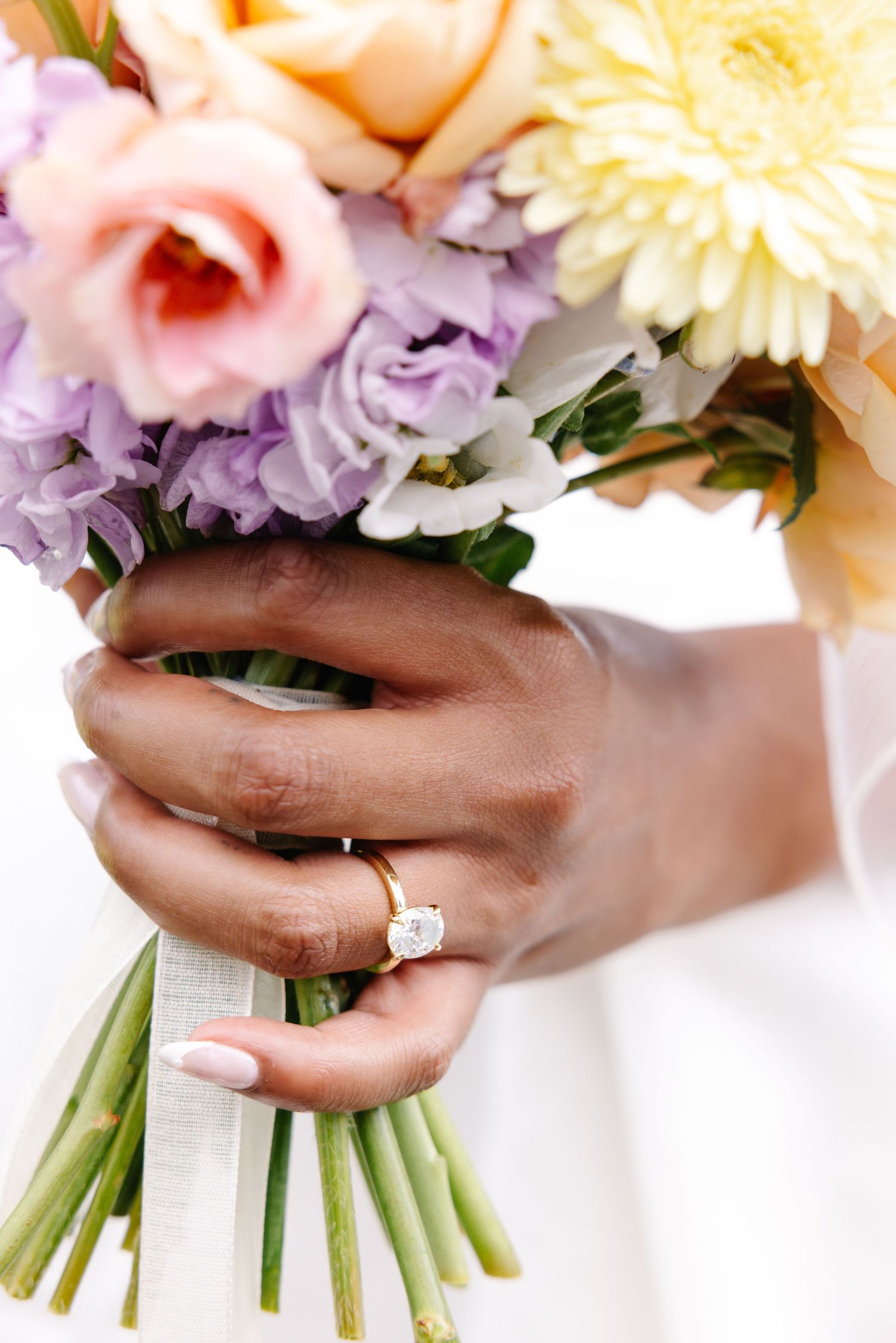 Elegant engagement ring displayed with pastel flower bouquet.