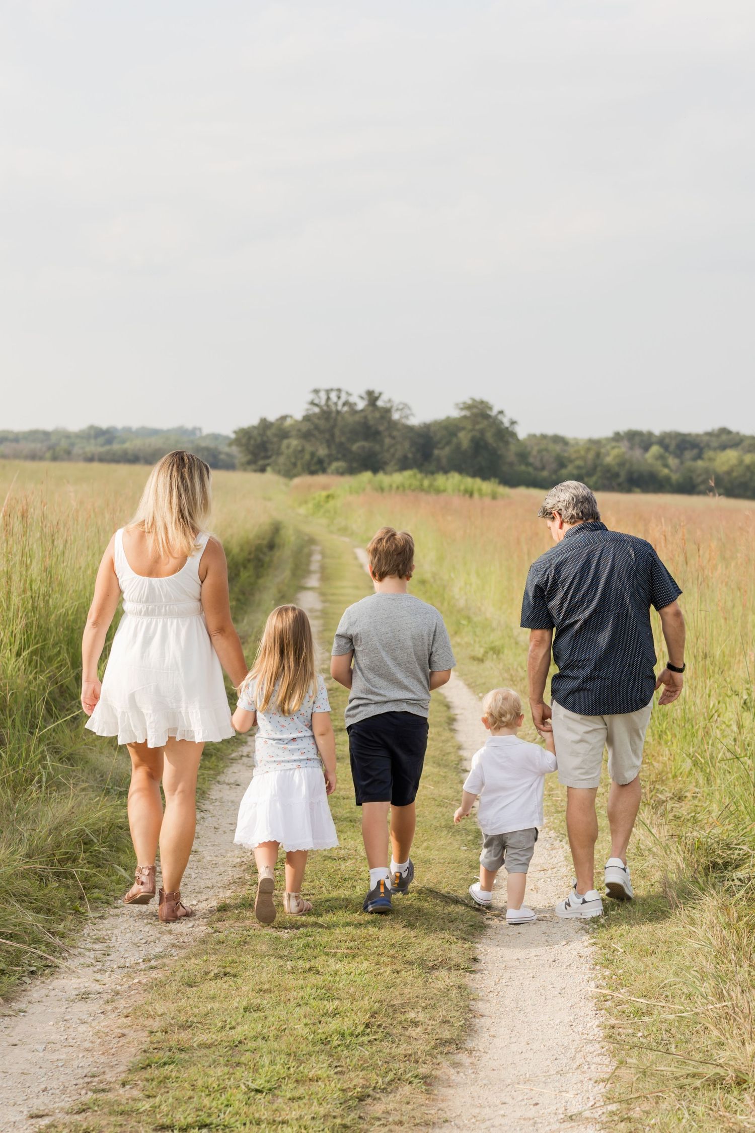 Group walking together on nature trail through tall grass field.