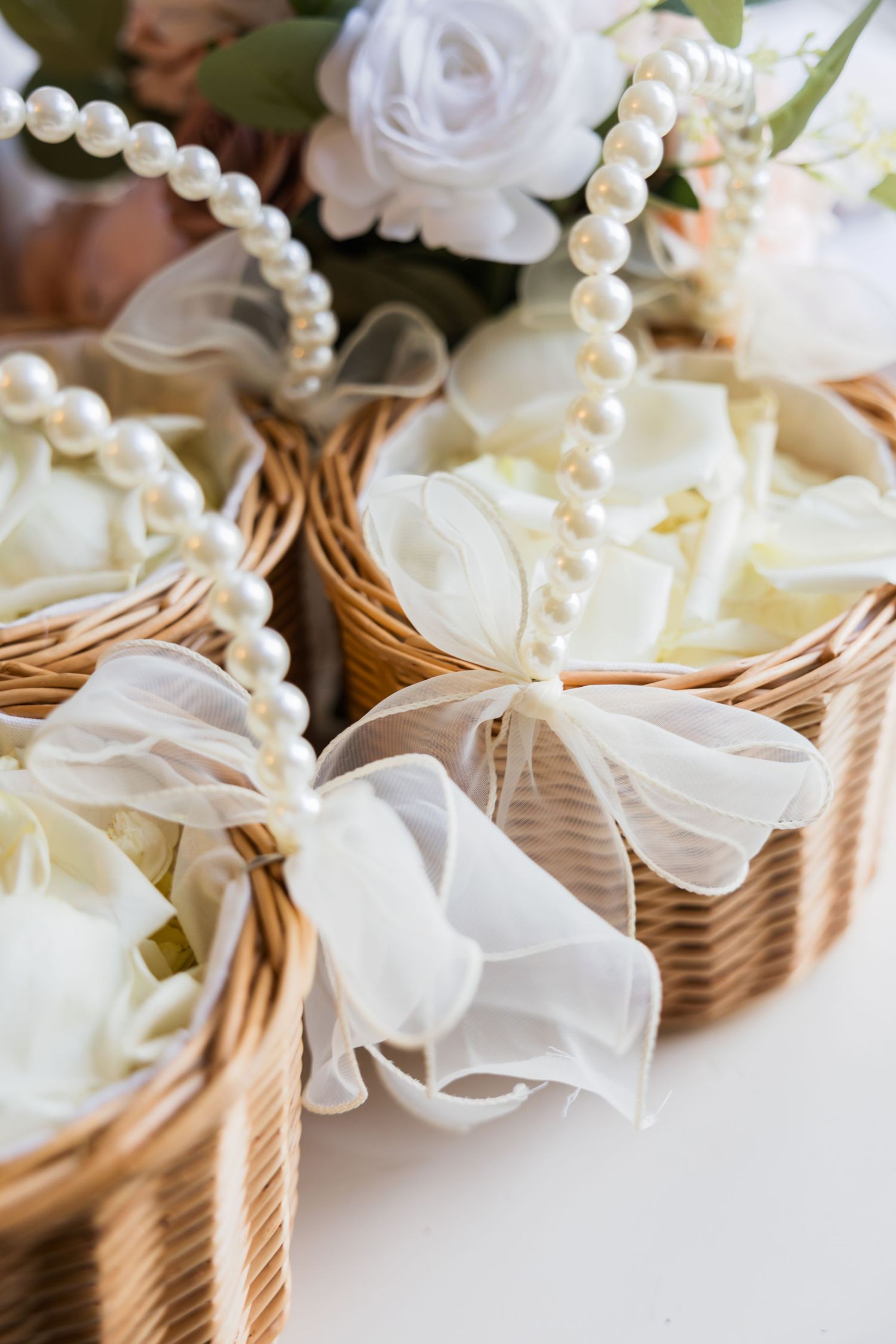 Decorative pearl strands and white ribbons arranged with woven basket details.