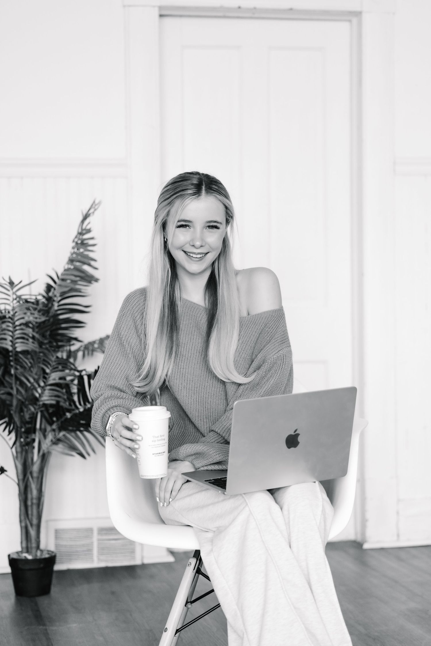 Person working on laptop with coffee in modern white office space with plants.