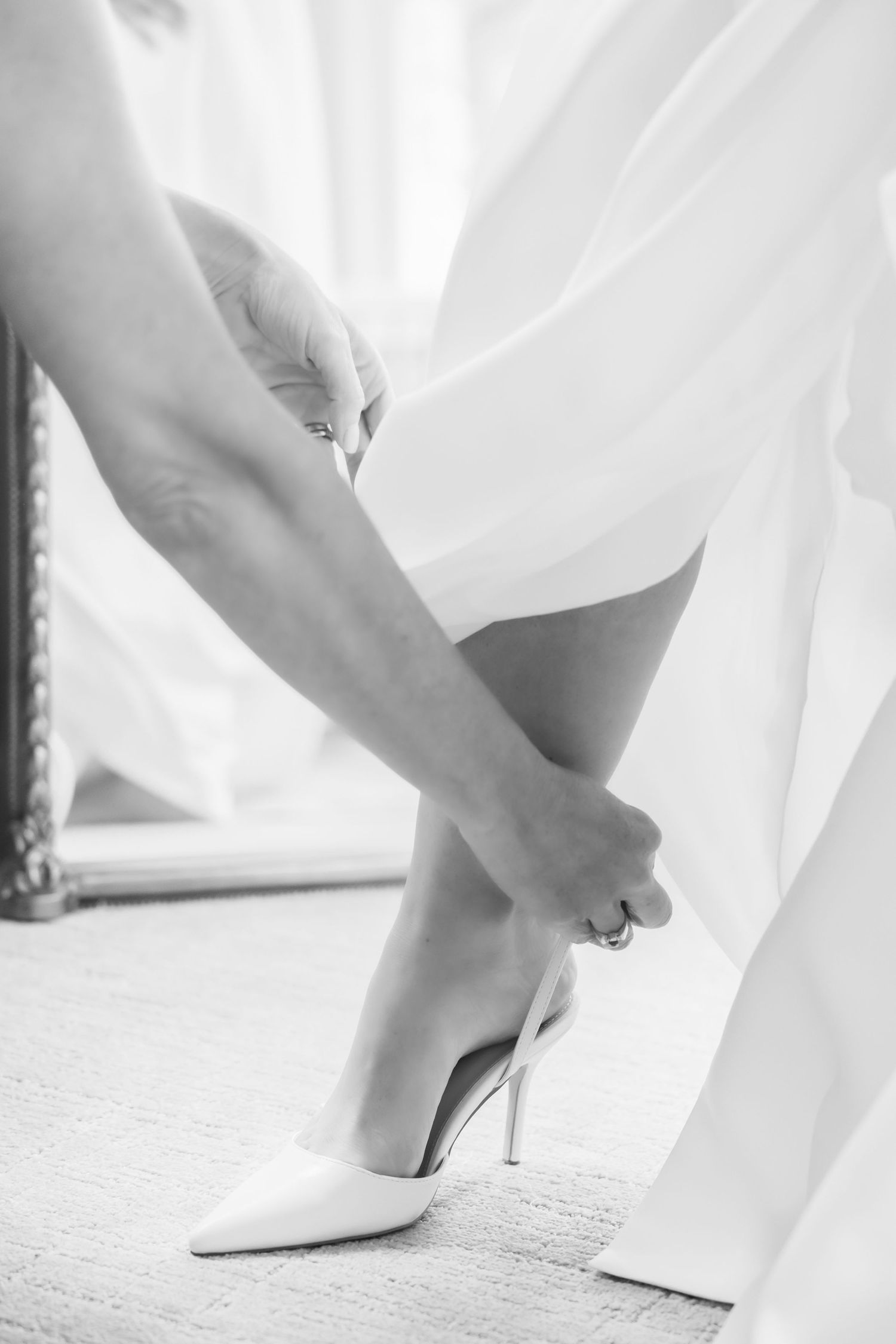 Close-up view of white high heels being put on during a wedding preparation.