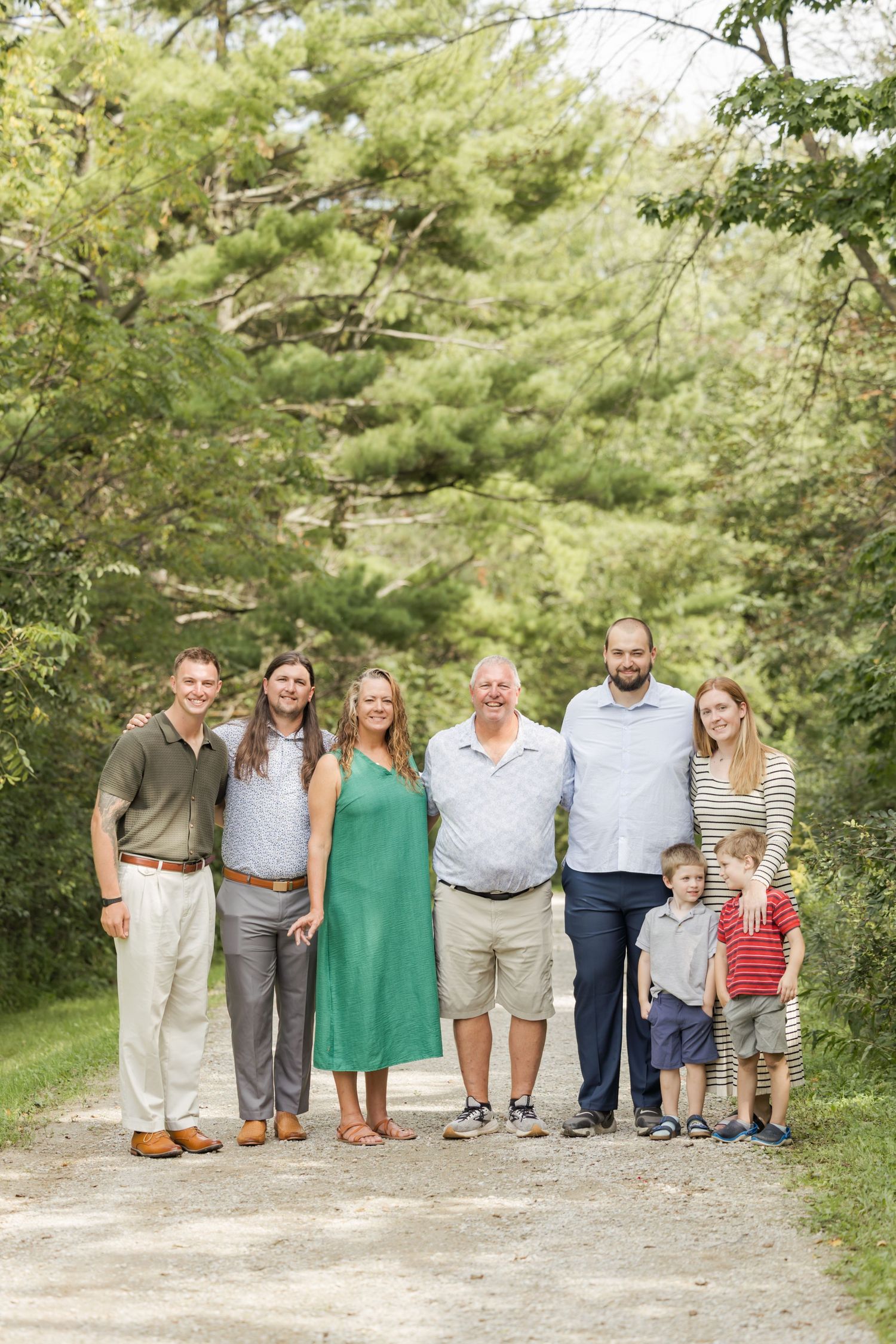 Large family group poses together on nature trail surrounded by pine trees.