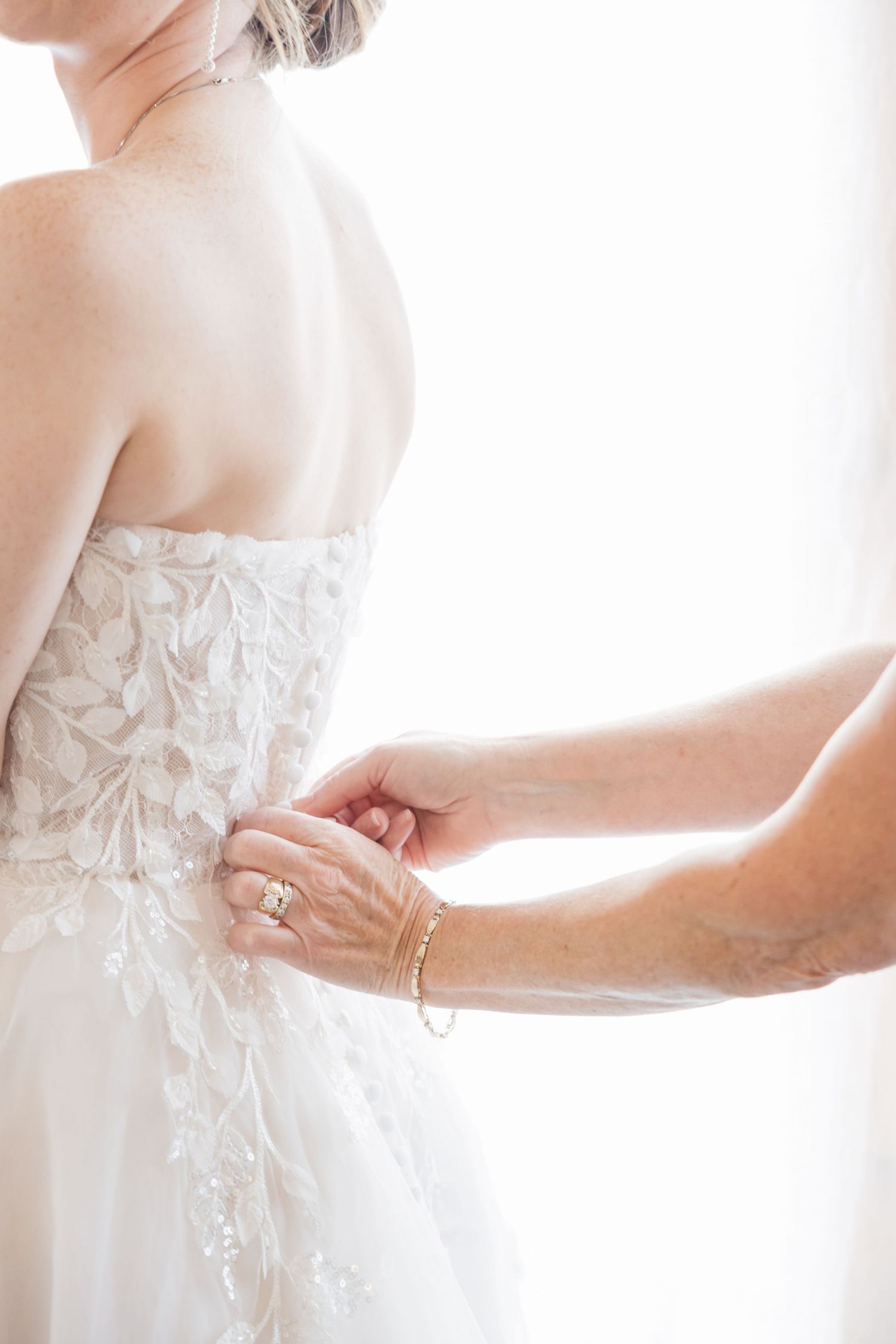 Close-up of white lace wedding dress details being adjusted.