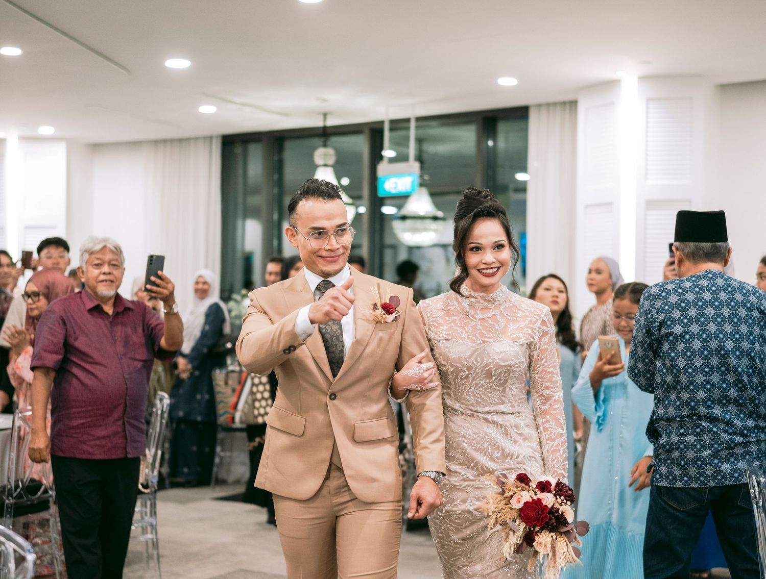 A couple walks down a hallway as they celebrate in elegant beige and sparkling formal attire at Malay wedding Novotel on Stevens.