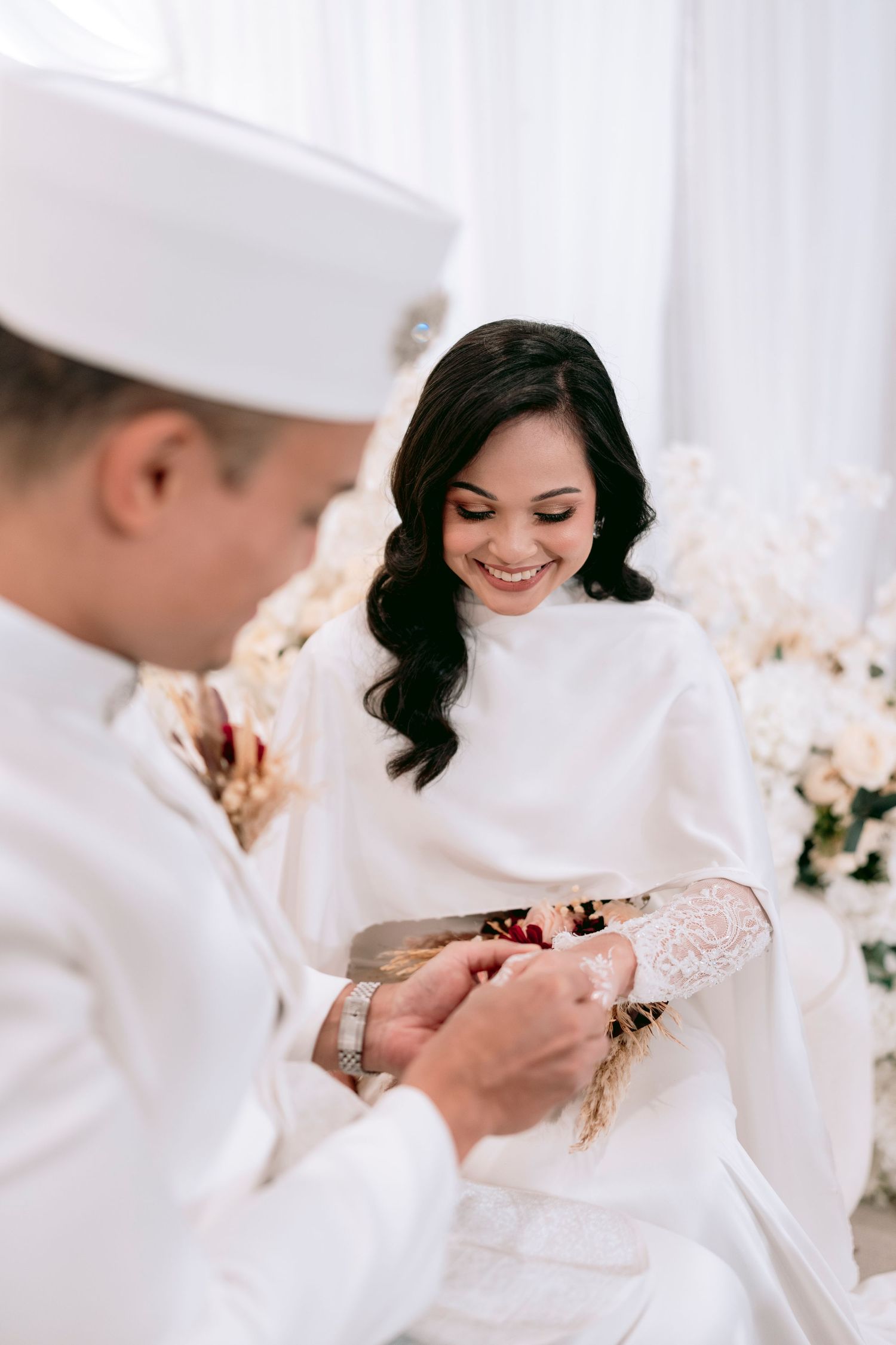 A traditional Malay wedding ceremony with the couple in elegant white traditional attire exchanging rings at Novotel on Stevens.