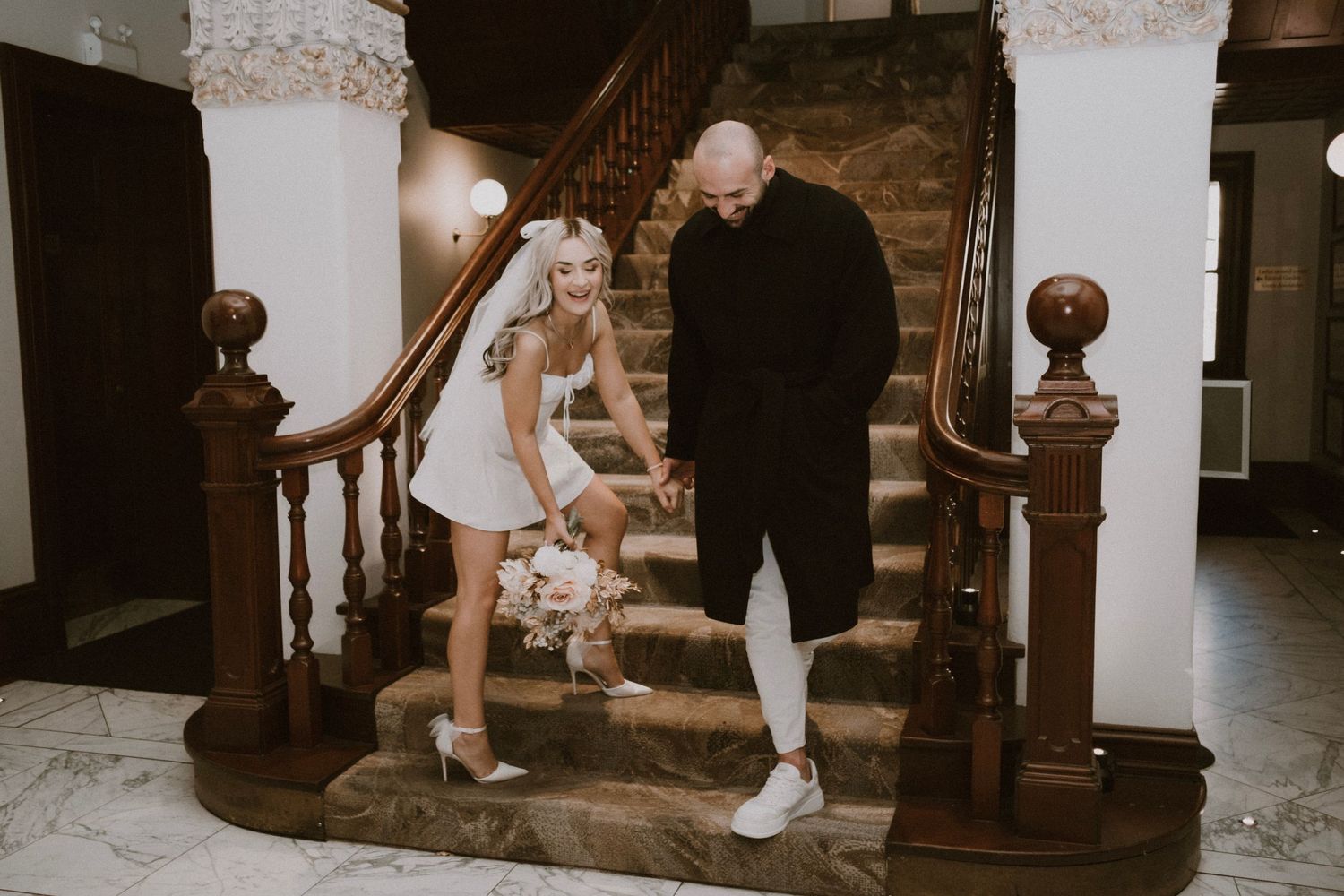 Couple descending vintage wooden staircase in casual attire.