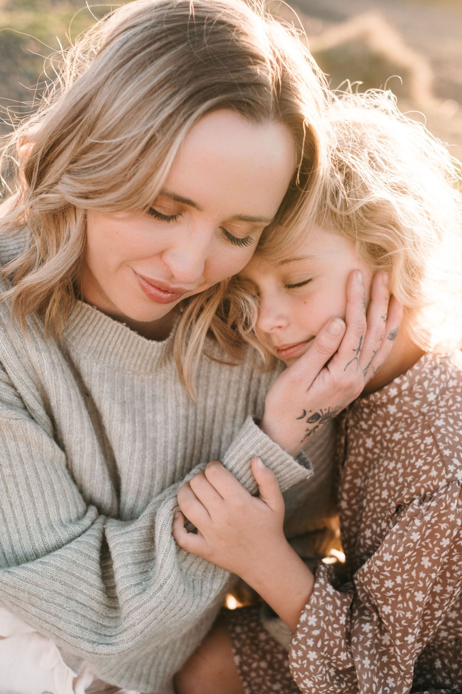 Tender moment between two people in warm sunset light wearing cozy sweaters.