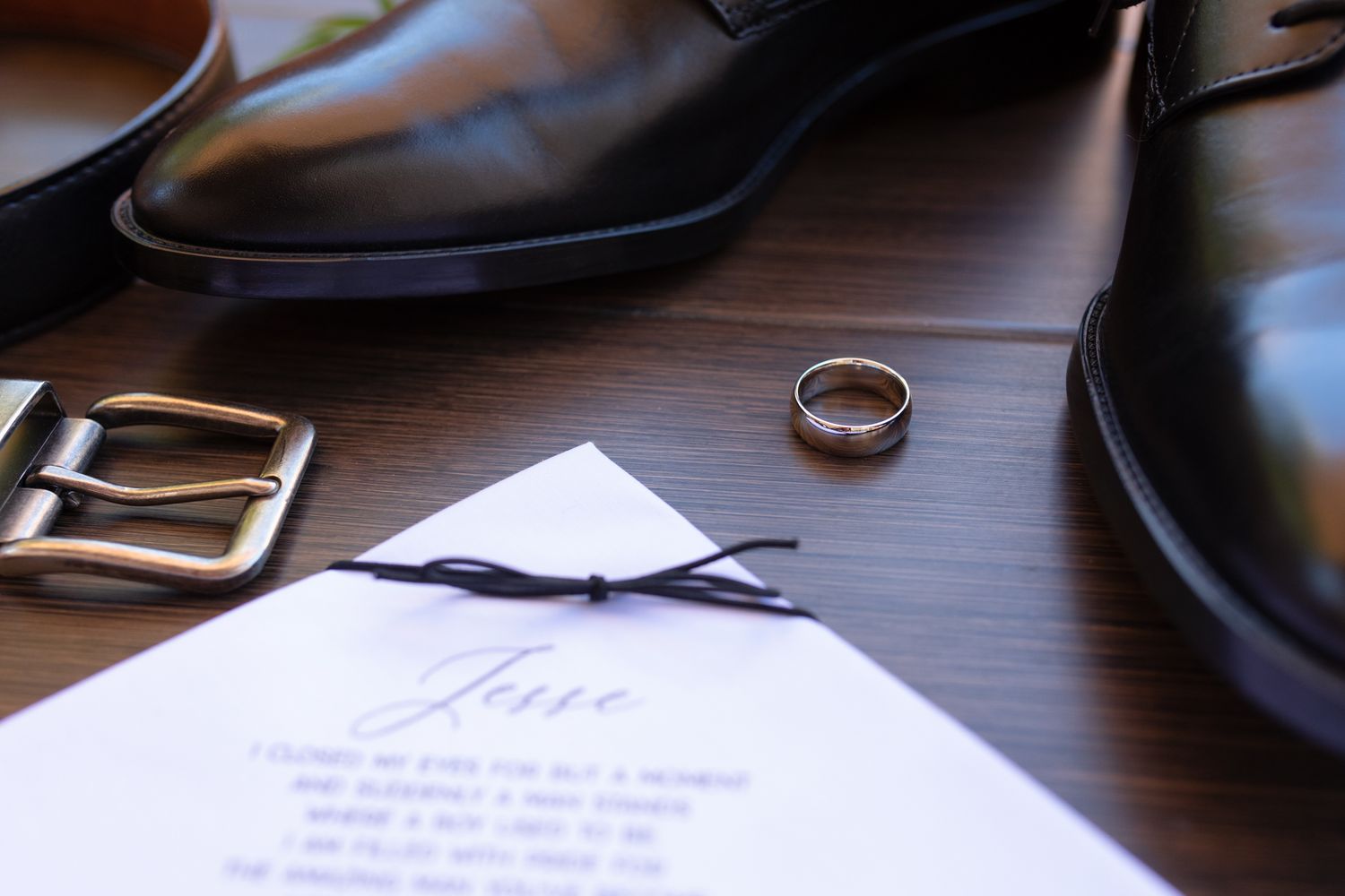 A collection of black leather dress shoes and accessories arranged on a wooden surface.