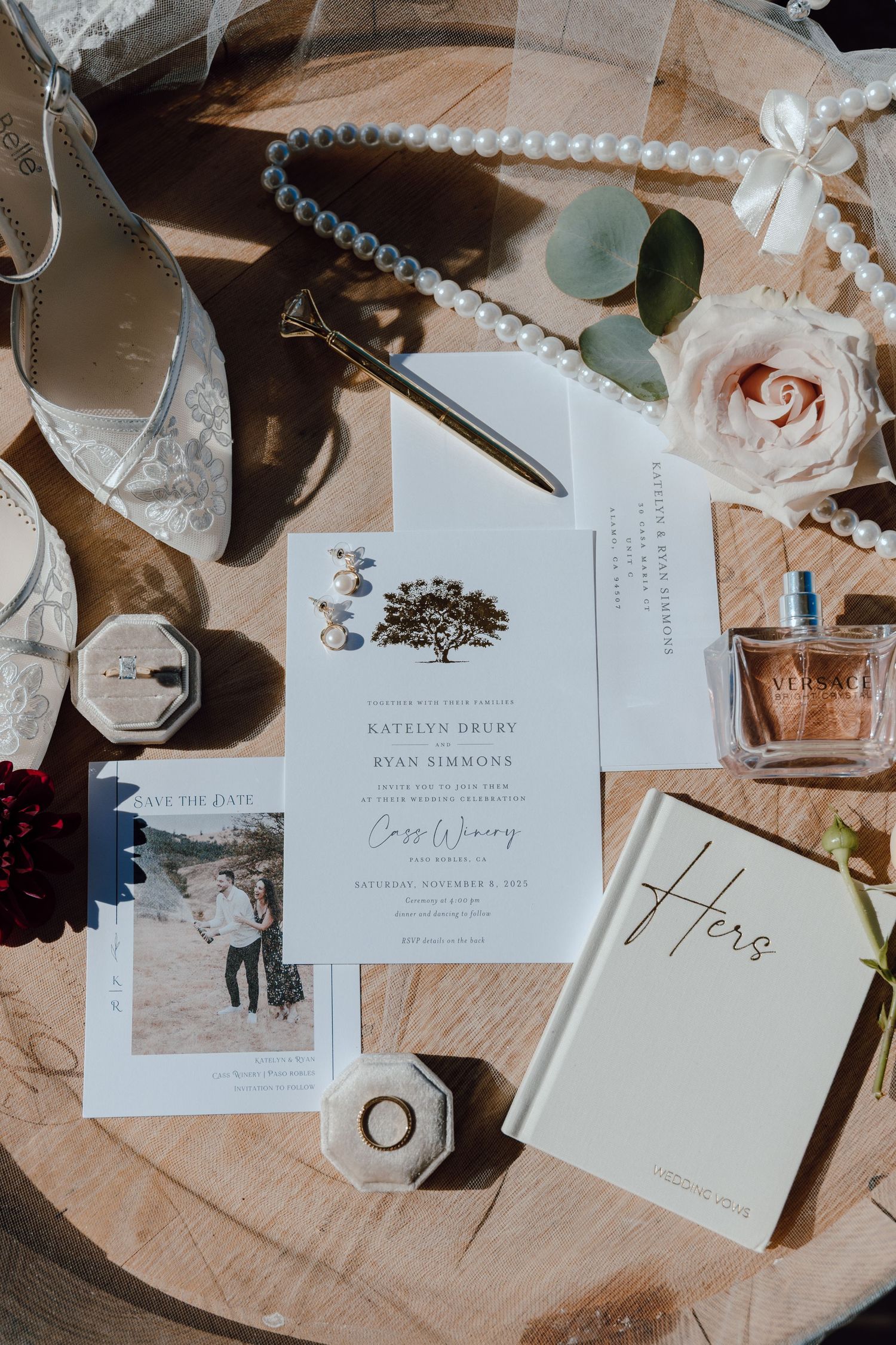 Wedding stationery and invitation details laid out on a wooden surface with roses and decorative elements.