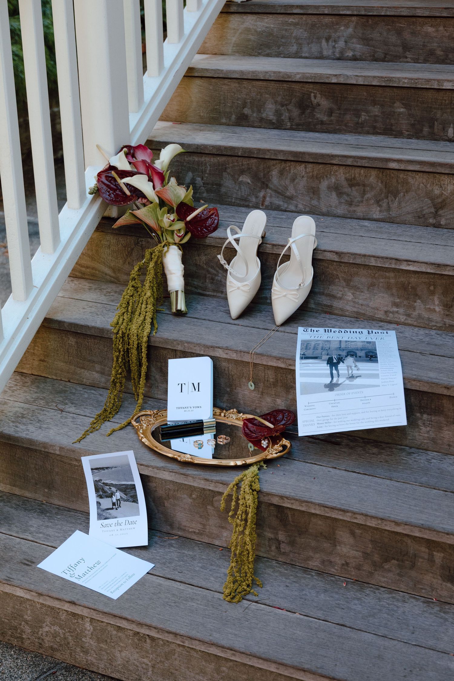Wedding details including white shoes, floral bouquets, and paper items arranged on rustic wooden stairs.